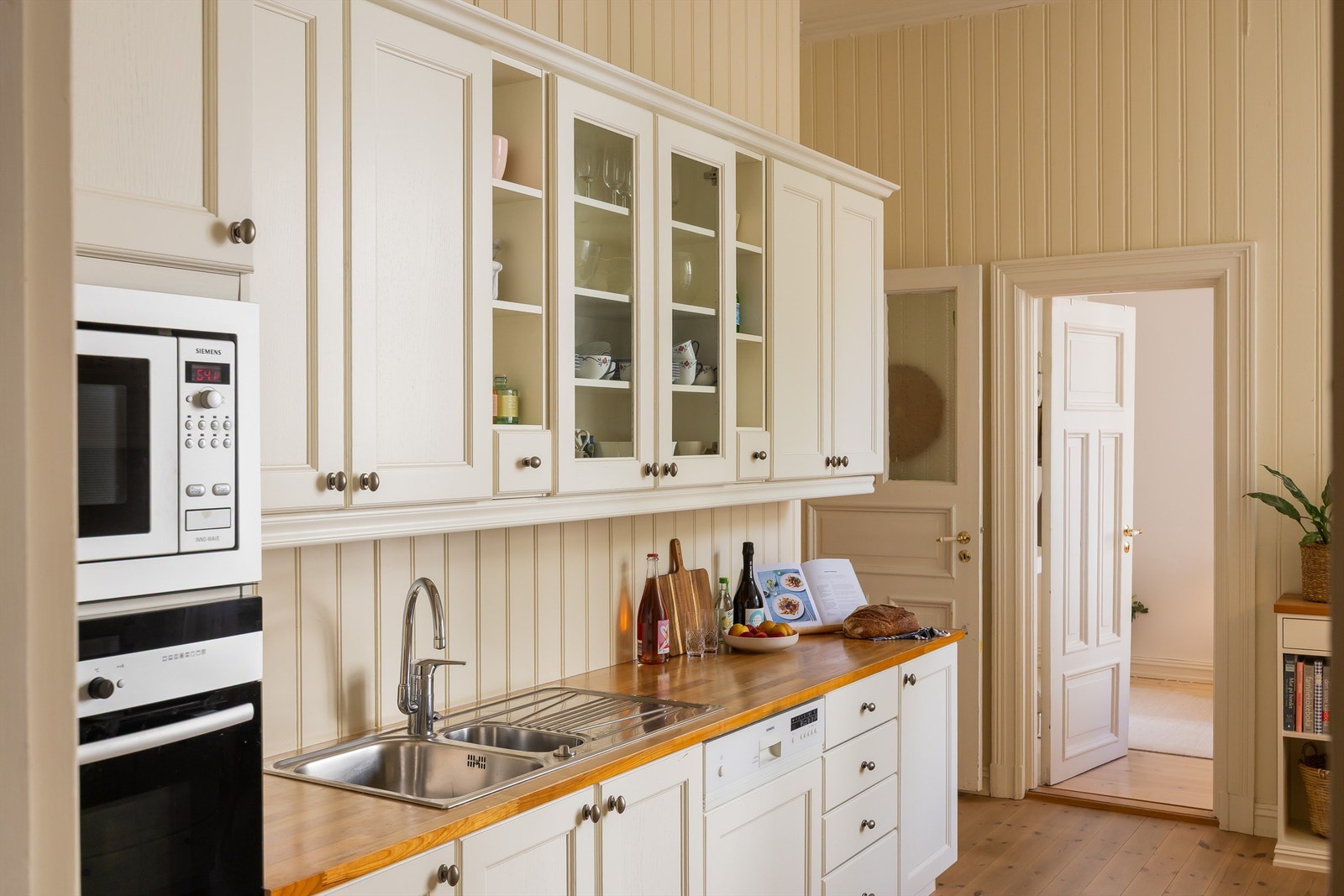 Benkeplate i tre og overskap med vitrinedører gir både karakter og praktisk oppbevaring. Galleribilde