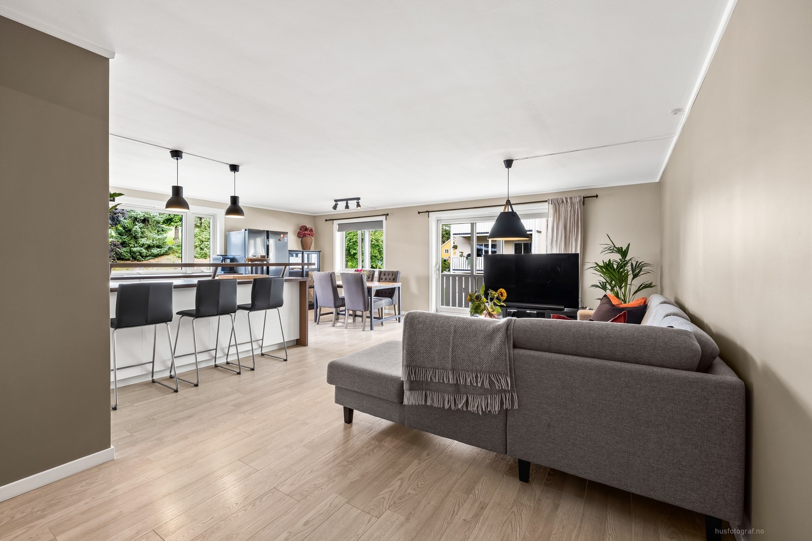 Åpen kjøkken- og stueløsning med sofaområde samt spiseplass Galleribilde