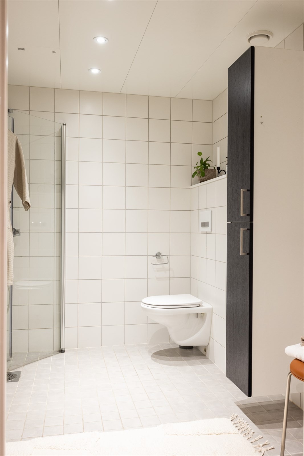 Badet inneholder veggmontert toalett, servant med innredning og dusjnisje med glassdører. Opplegg til vaskemaskin. Galleribilde