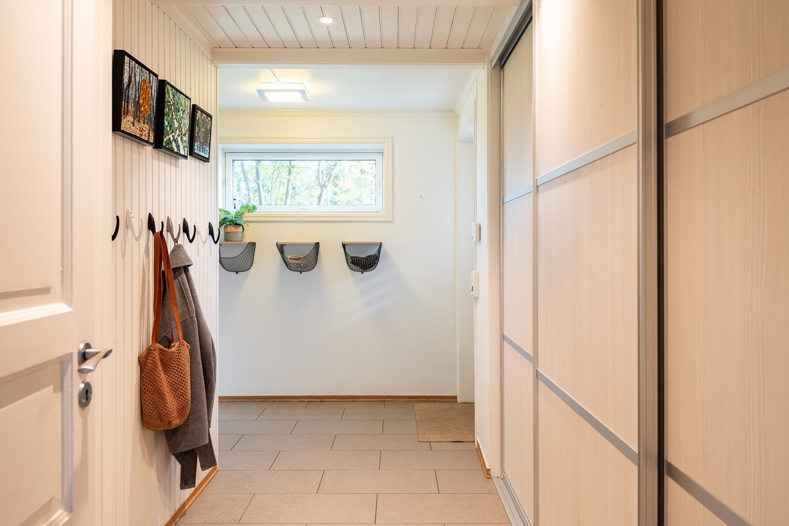 Innbydende og romslig entré på hele 12m² med god plass til oppbevaring av både sko og yttertøy. Til høyre for bildet er det også etablert en praktisk skyvedørsgarderobe - perfekt for ekstra med lagringsplass. Galleribilde