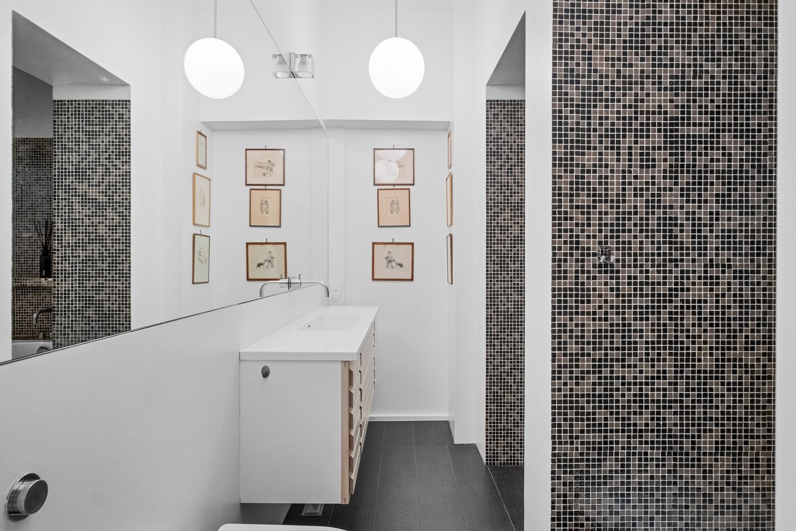 Stilrent baderom med vegghengt toalett, dusj og badekar, samt god oppbevaringsplass under servant. Galleribilde