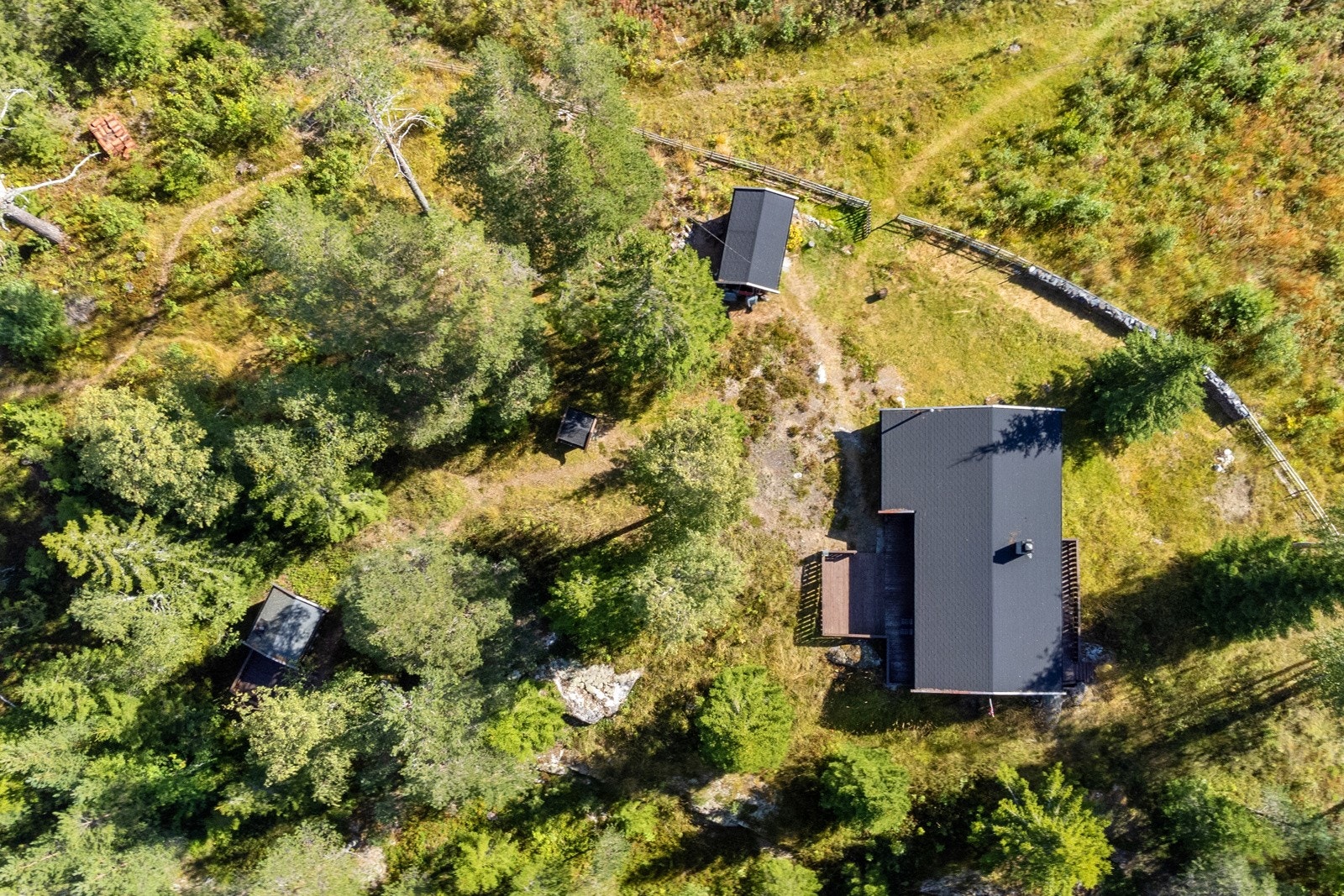 Eiendommen består av hytten, to frittstående bygninger, og en brønn. Galleribilde