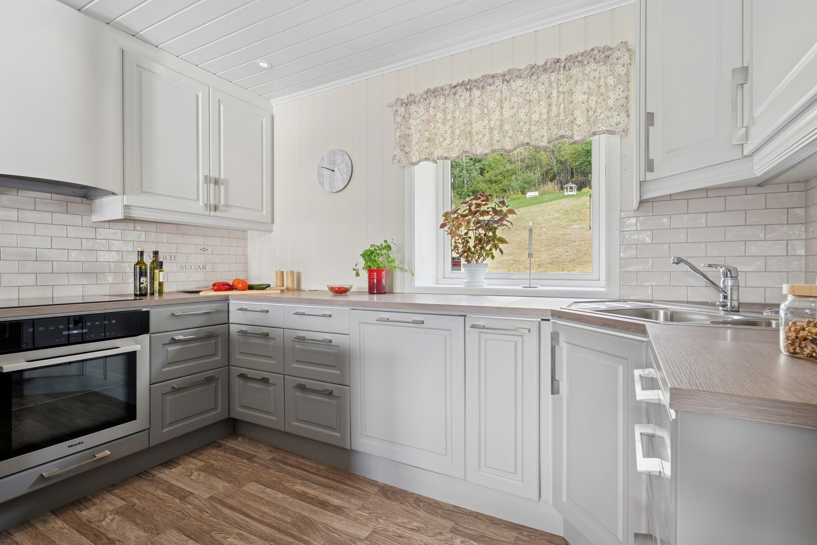 Kjøkkenet har profilerte fronter og benkeplate av laminat. Den store vindusflaten gjør at kjøkkenet oppleves lyst og luftig. Galleribilde