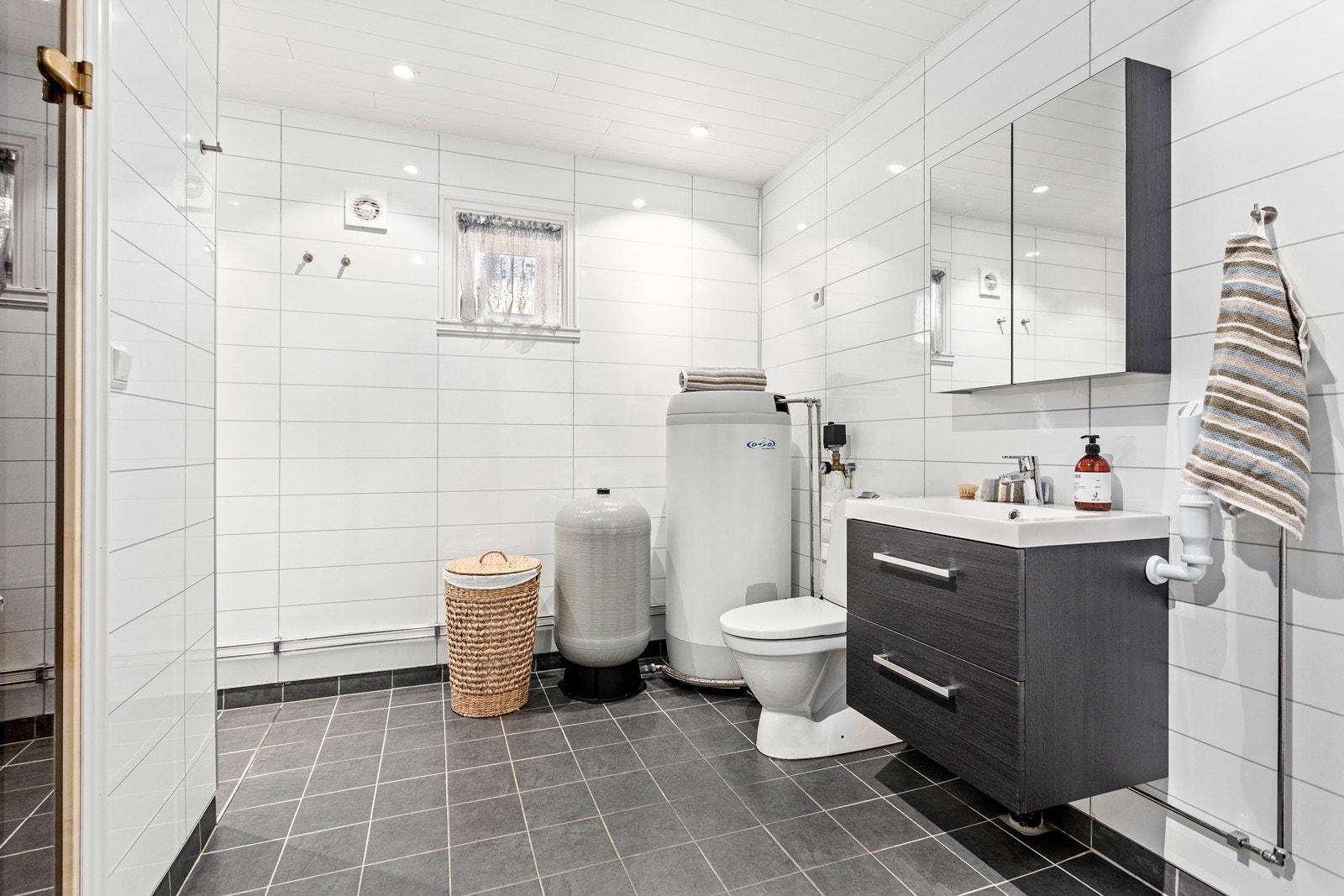 Badet har flislagt golv og er utstyrt med baderomsinnreinng, toalett og dusjhjørne. Galleribilde