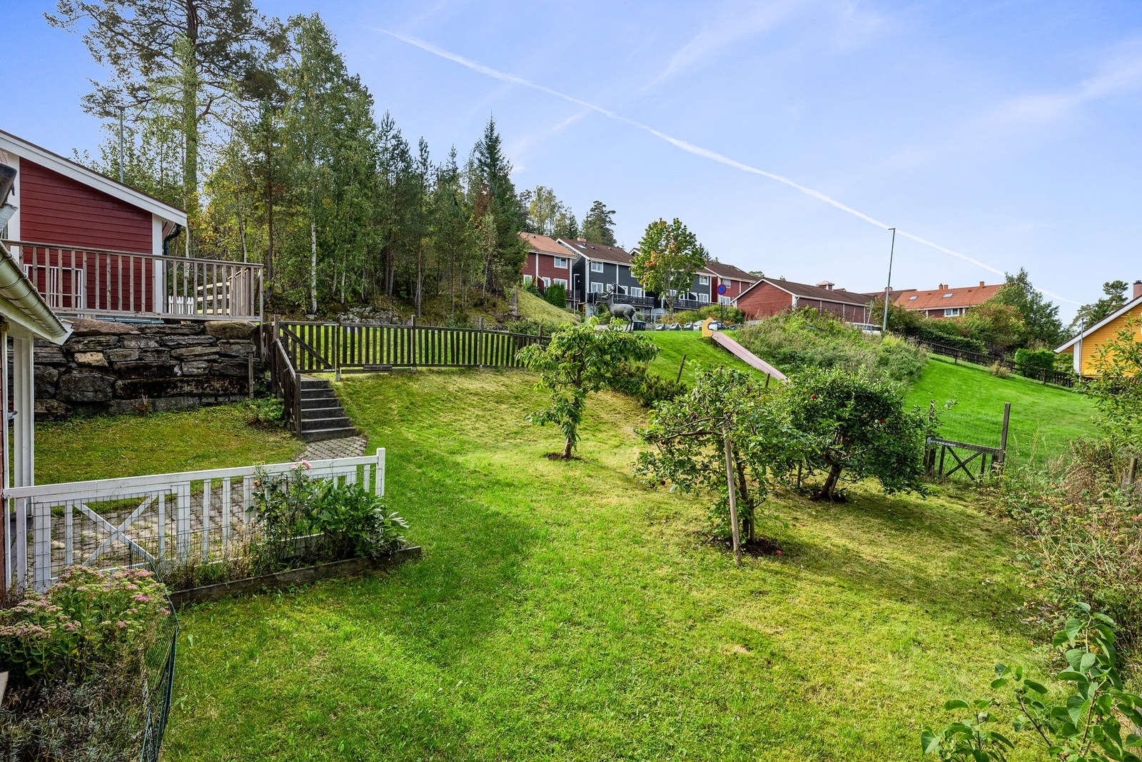 Den vestvendte hagen byr på grønn plen, blomsterbed og egne frukttrær. Galleribilde