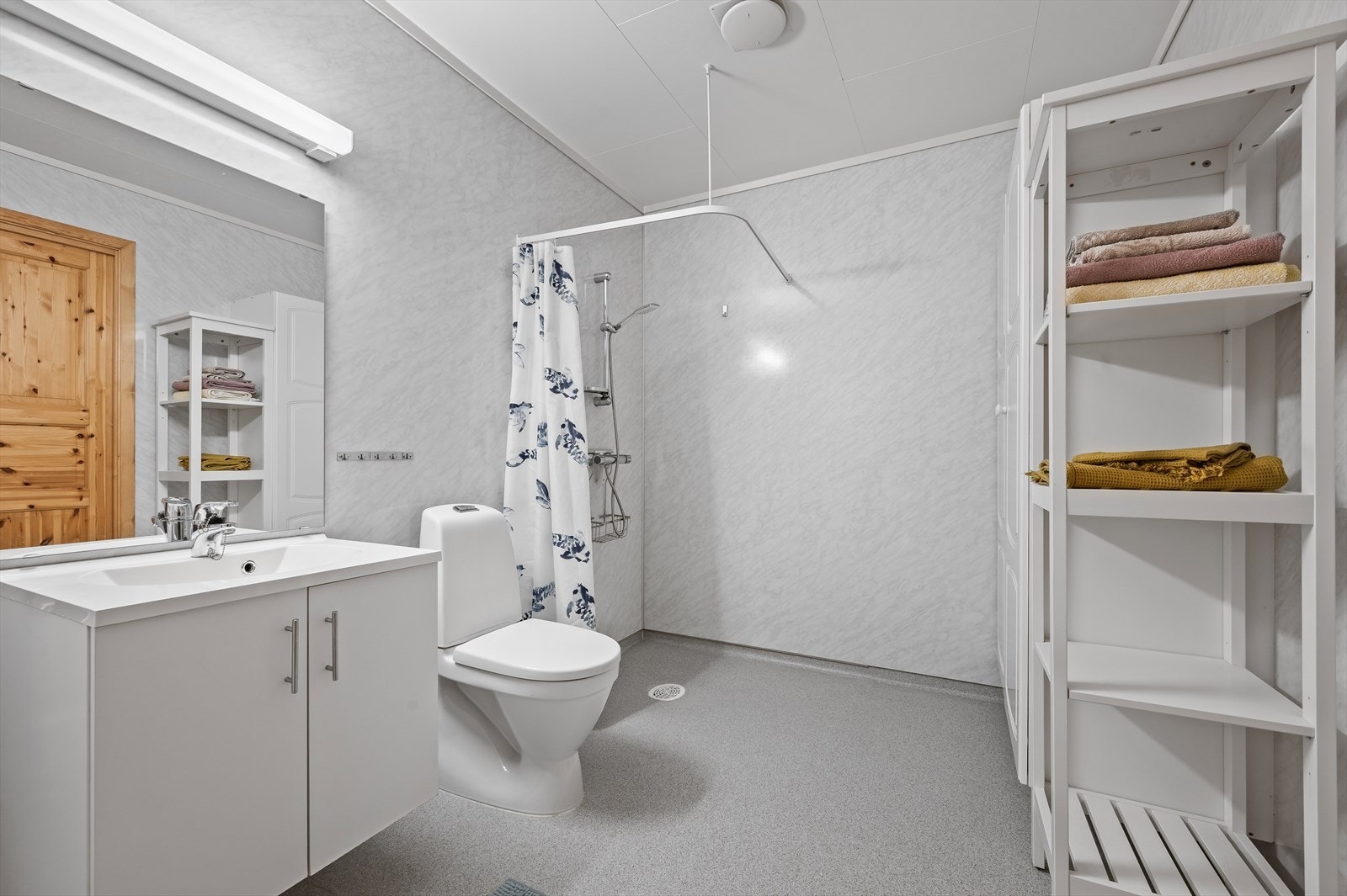 Badet inneholder dusjhjørne, toalett og servant med speil og over/underskap. Galleribilde