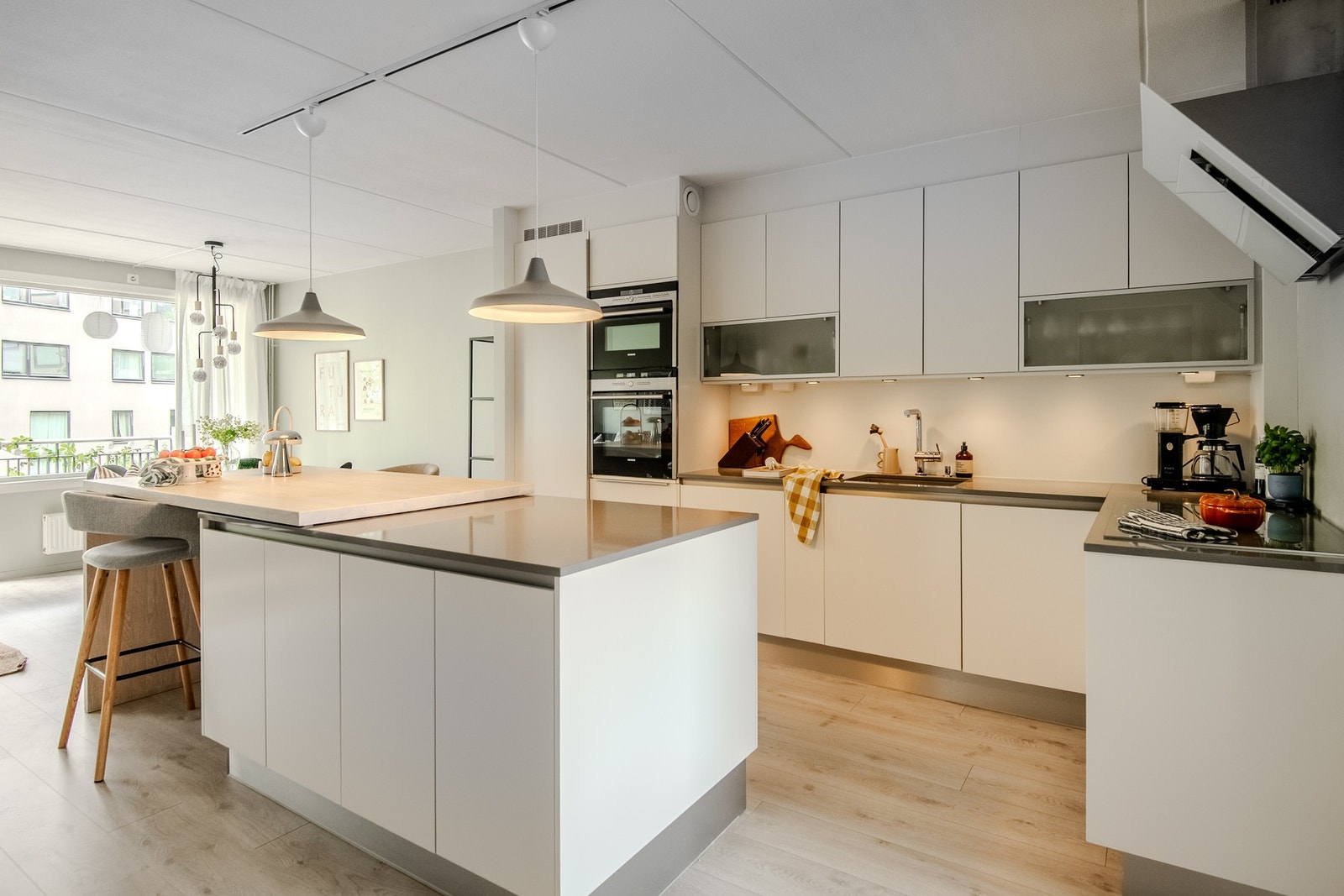 Kjøkkenet fremstår som stilrent og funksjonelt, med glatte, hvite fronter og en benkeplate i hovedsak av stein som gir et eksklusivt preg. Galleribilde