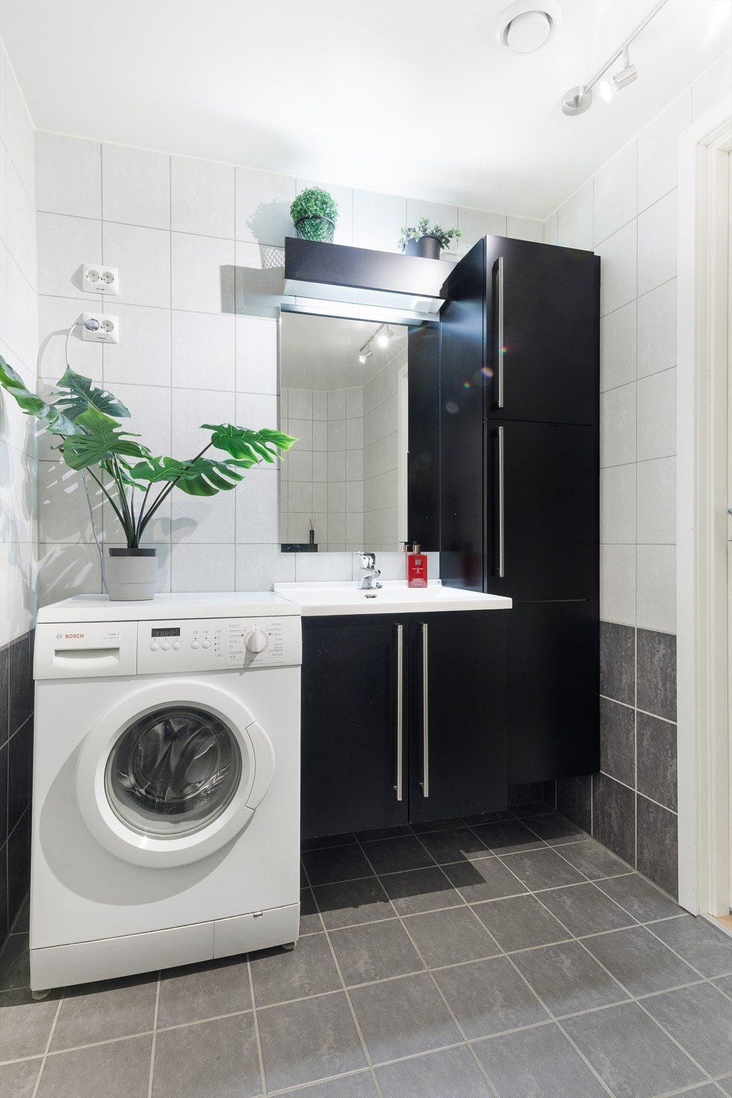 Badet er utstyrt med dusj, vegghengt toalett, baderomsinnredning og speil, samt opplegg for vaskemaskin. Galleribilde