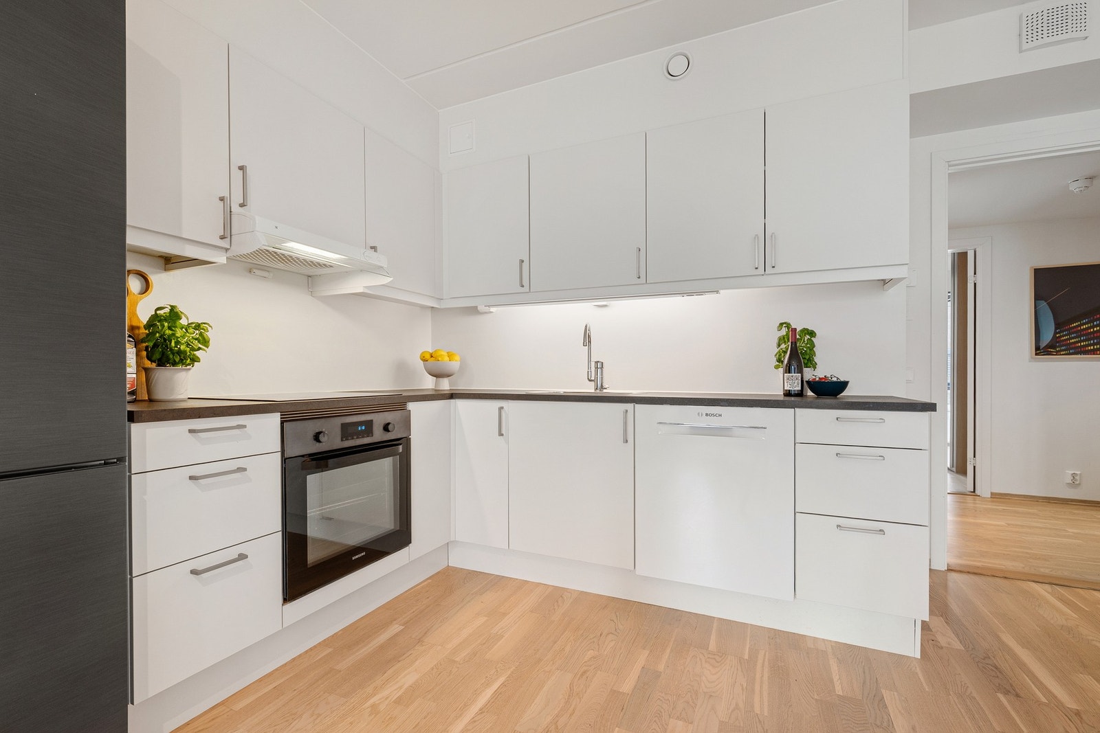 En moderne kjøkkeninnredning med hvite, glatte fronter og benkeplate av laminat Galleribilde