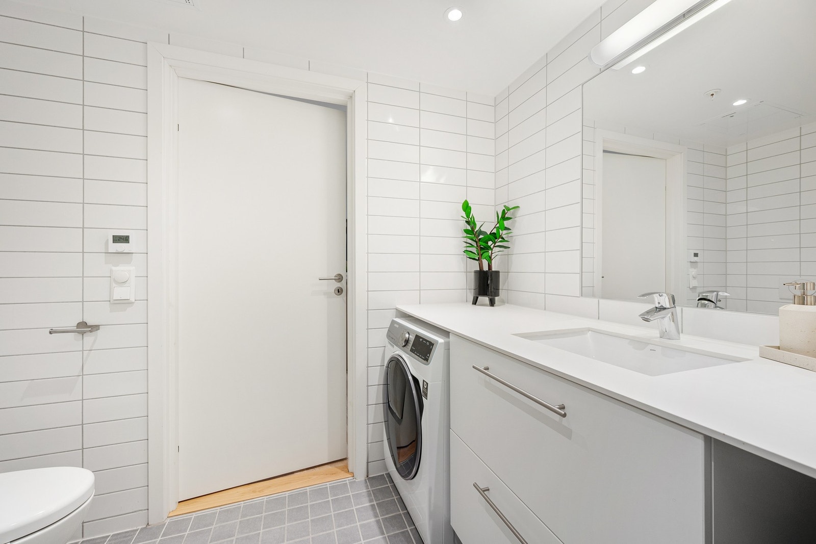 Innredningen består av servant med dobbelskuff med speil over, vegghengt toalett og dusjnisje med innfellbare glassdører. Det er opplegg for vaskemaskin Galleribilde