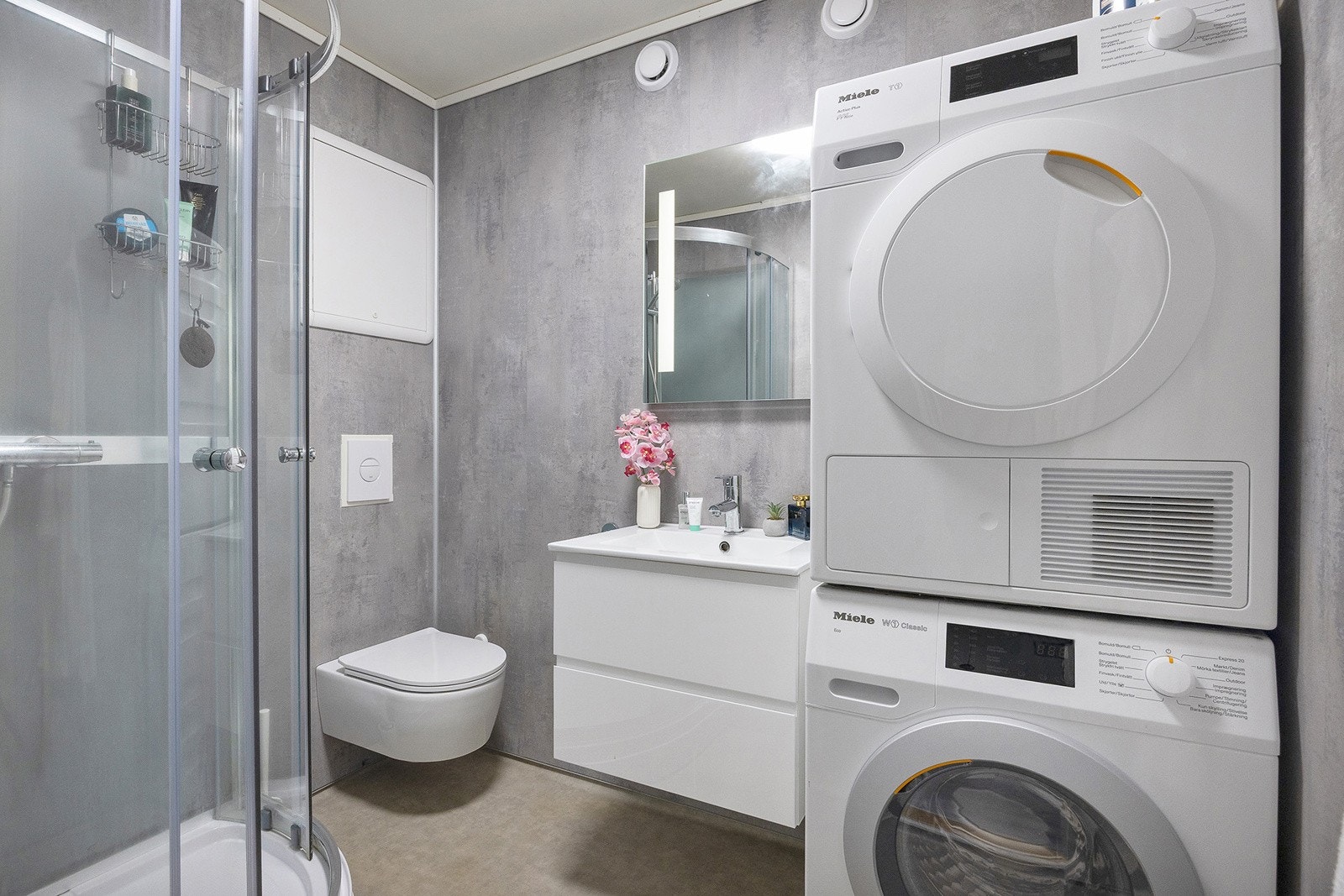 Bad med varme i gulv. Badet er pusset opp i 2021 og inneholder dusjkabinett, servant med skuffeseksjon, speil med belysning, vegghengt toalett og opplegg for vaskemaskin/tørketrommel. Galleribilde