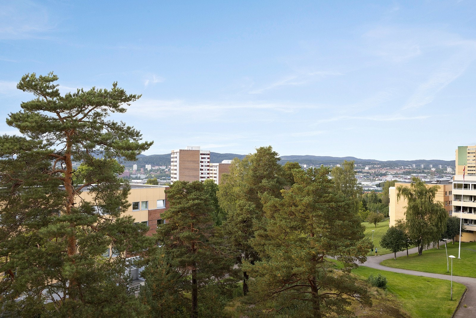 Opparbeidet utearealer med sittegrupper, lekeplasser, beplantning, trær, ballbinge, gressplener og bilfrie internveier. Galleribilde