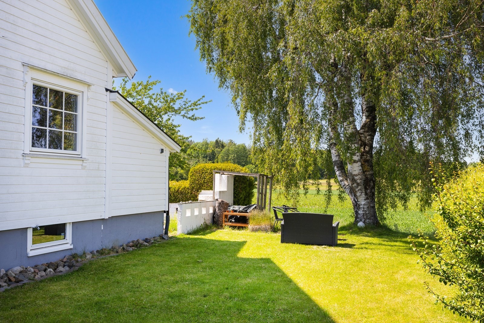 Tomten er opparbeidet med plen, beplantning og en trivelig terrasseplatting. Galleribilde