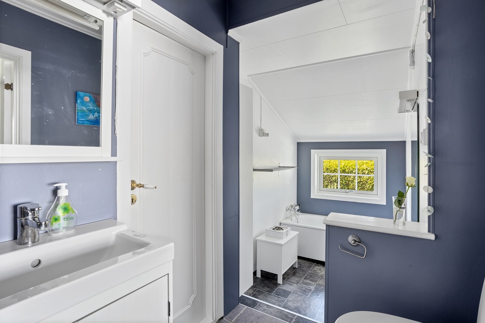 Badet er innredet med servantskap, dusjkabinett, håndkletørker, badekar og WC. Galleribilde