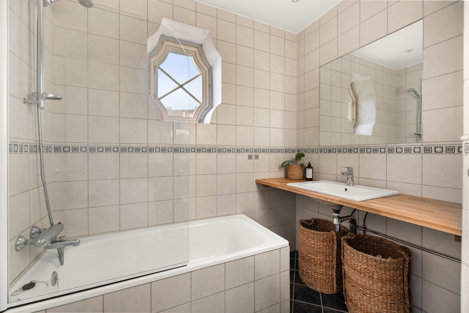 Et delikat flislagt bad (2007) med gulvvarme. Utstyr på badet inkluderer innfliset badekar med dusjvegg i herdet glass på hengsler. Galleribilde