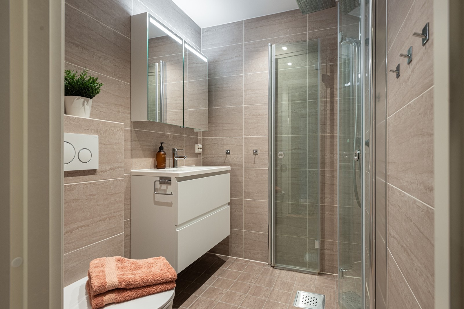 Bad 2 har direkte adkomst fra hovedsoverommet og er innredet med vegghengt toalett, servant integrert i innredning, speilskap med belysning samt dusjhjørne med svingbare glassdører Galleribilde