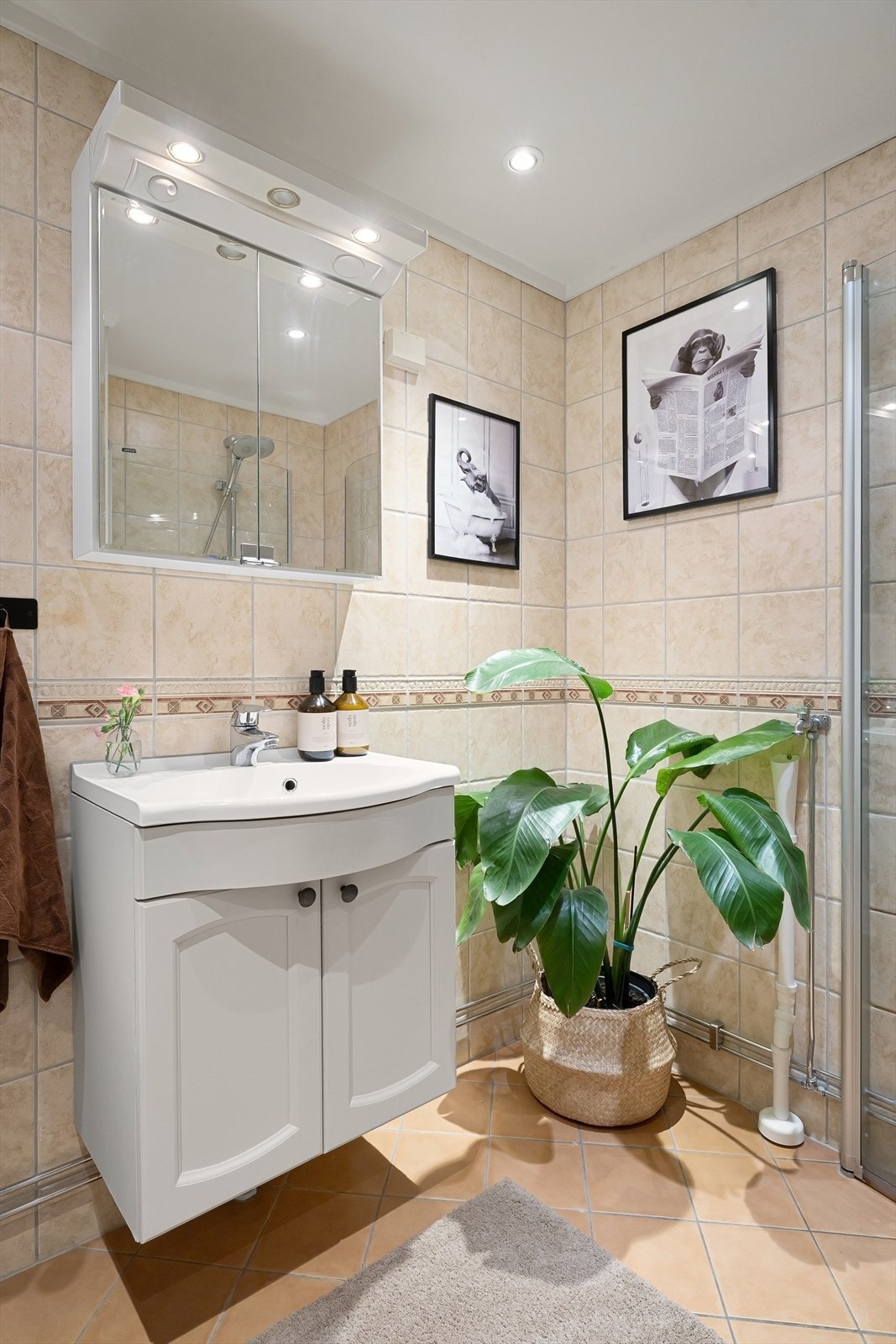 Videre er baderommet innredet med servant med skapinnredning og speilskap med belysning over samt vegghengt skap Galleribilde