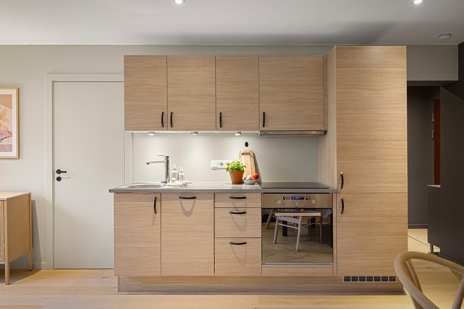 Integrerte hvitevarer som smal oppvaskmaskin, stekeovn, koketopp med ventilator over og kjøl-/fryseskap Galleribilde