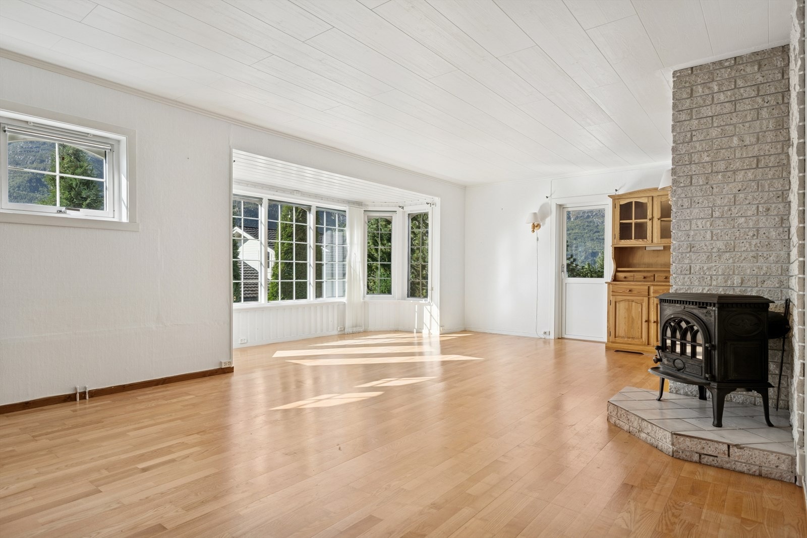 Et sjarmerende karnapp gir ekstra romfølelse og tilfører en lun atmosfære, samtidig som det fremhever lysinnslippet. Den flotte vedovnen i klassisk stil gir både varme og hygge på kjølige kvelder. Galleribilde