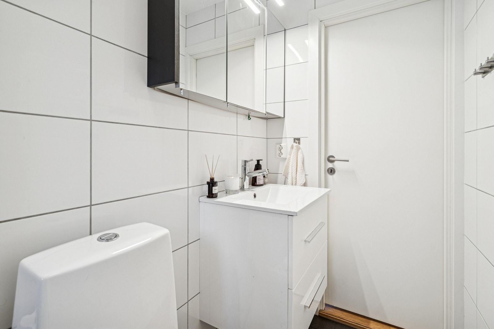 Baderomsinnredningen har hvite høyglansfronter og består av en heldekkende servant på en skuffeseksjon og et dobbelt speilskap med belysning. Galleribilde