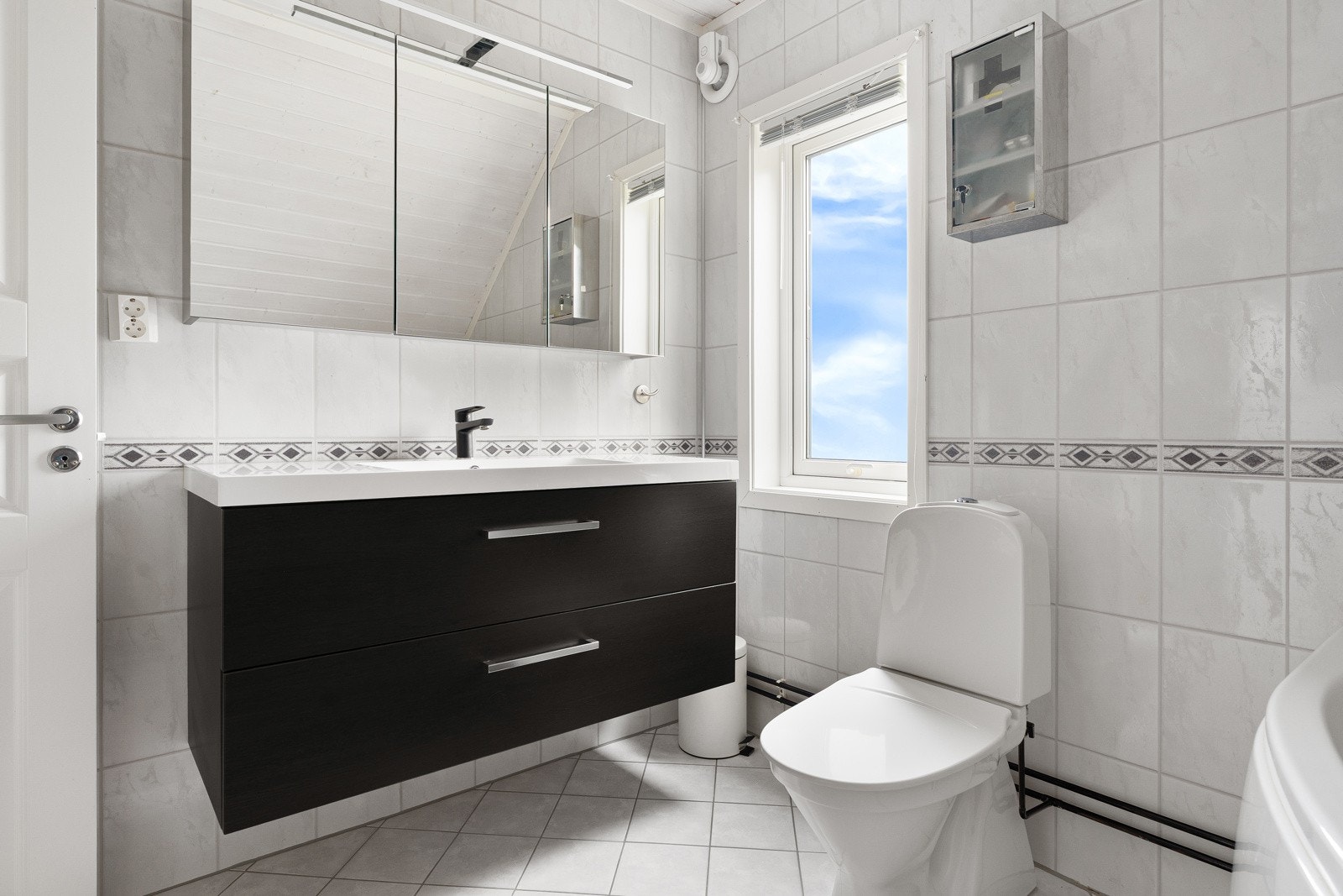 Baderom på loft med moderne innredning, speilskap og badekar.