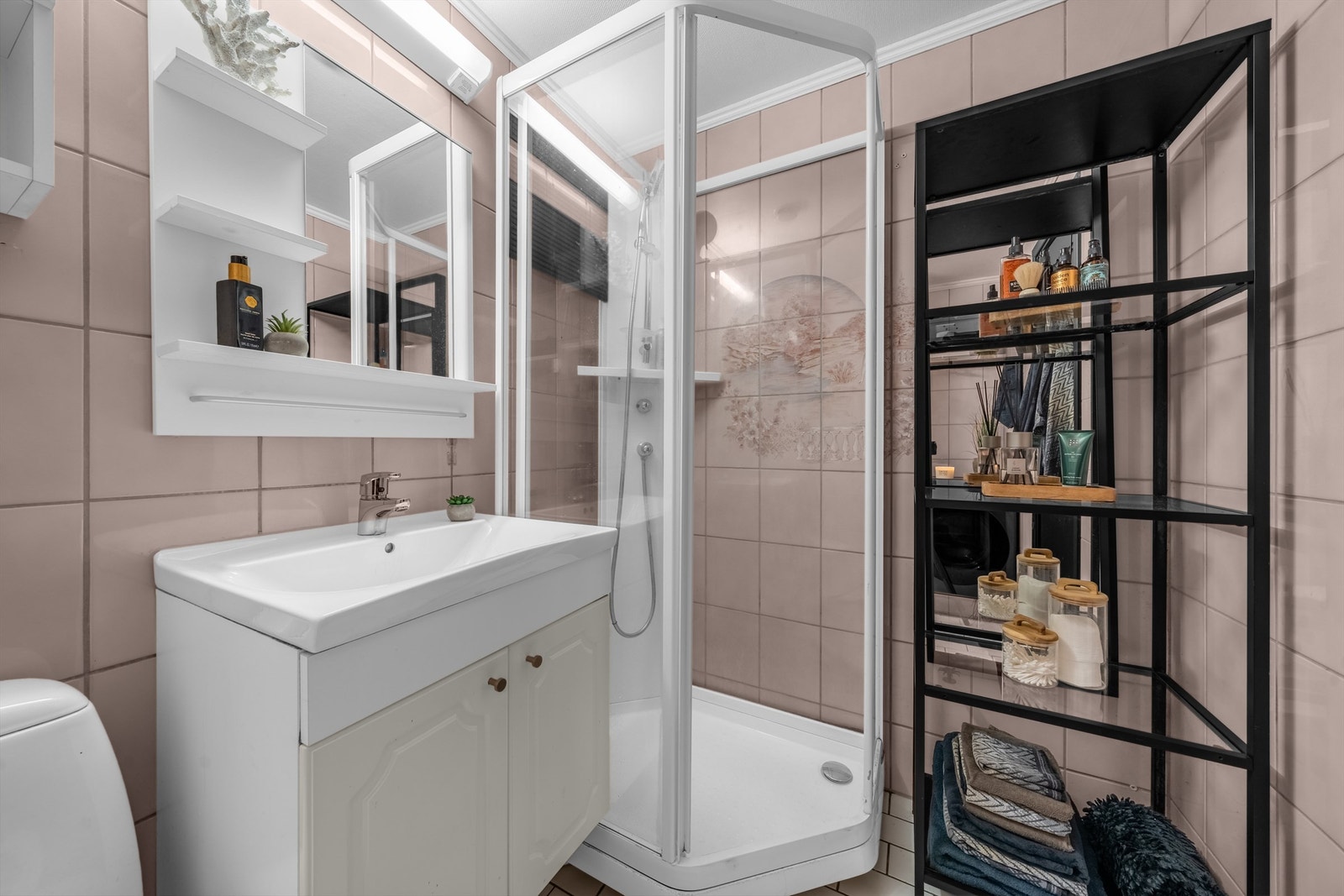 Eldre bad som har toalett, dusjkabinett og innredning med profilerte skapfronter, heldekkende servant og speil med belysning i overkant Galleribilde