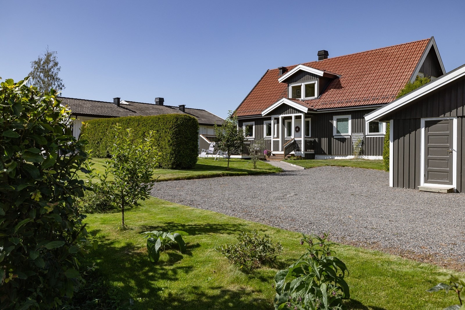 Romslig, gruset gårdsplass og en hellebelagt sti som leder til boligens inngangsparti. Galleribilde