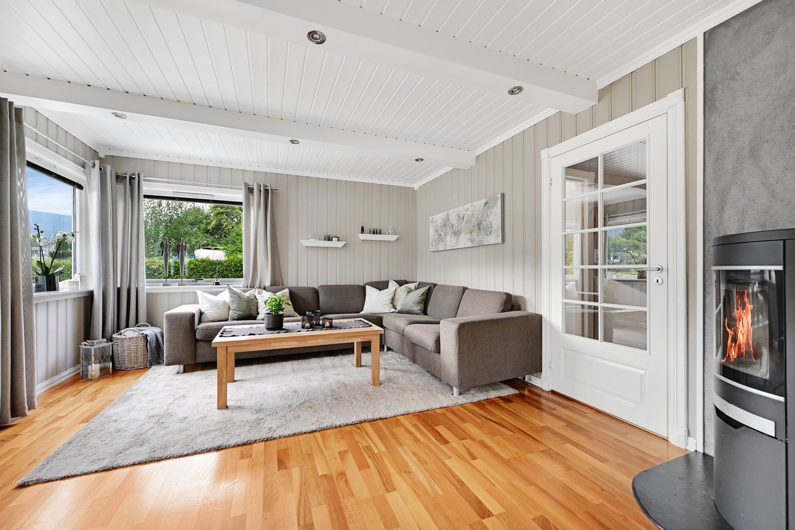 Videre inn er stuen med plass til salong av god størrelse. Her er det montert en vedovn av nyere type for effektiv oppvarming. Galleribilde