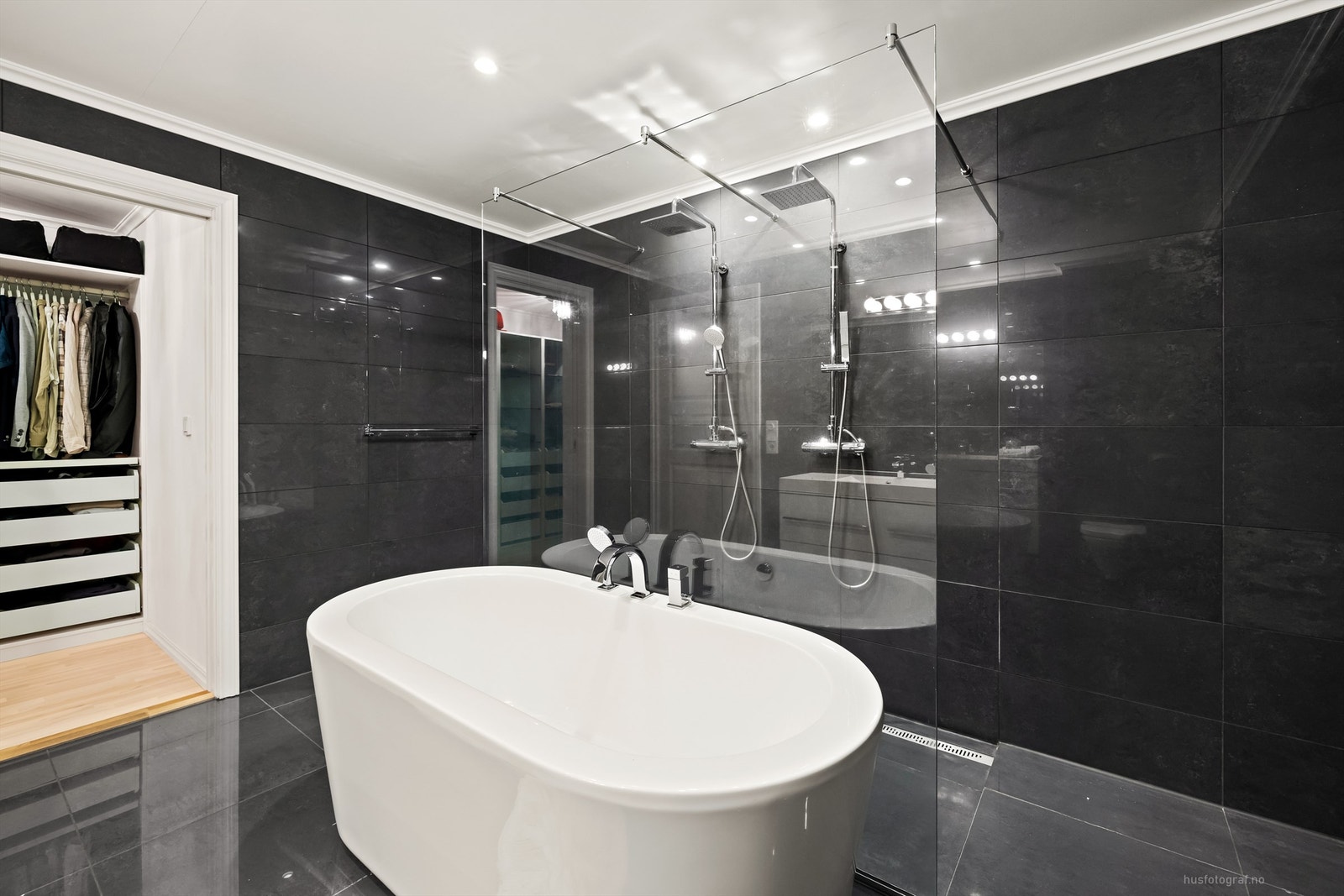 Badet har badekar og dusjnisje som har to veggmonterte regnfallsdusjer Galleribilde