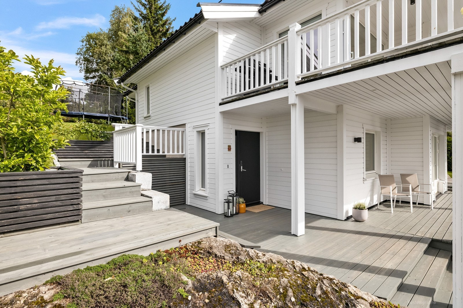 Terrassen er over flere halvplan og strekker seg rundt tre sider av boligen Galleribilde