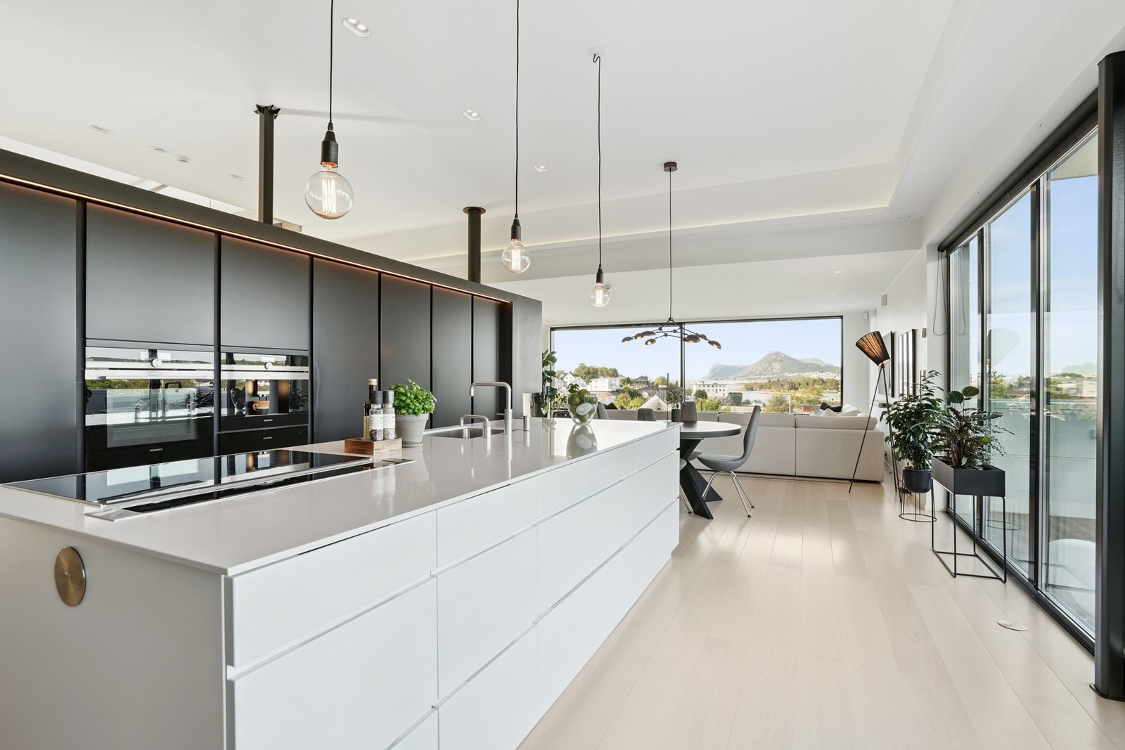 Stilrent kjøkken med integrerte hvitevarer. Sosial og stor kjøkkenøy med delikat benkeplate av Corian. Galleribilde