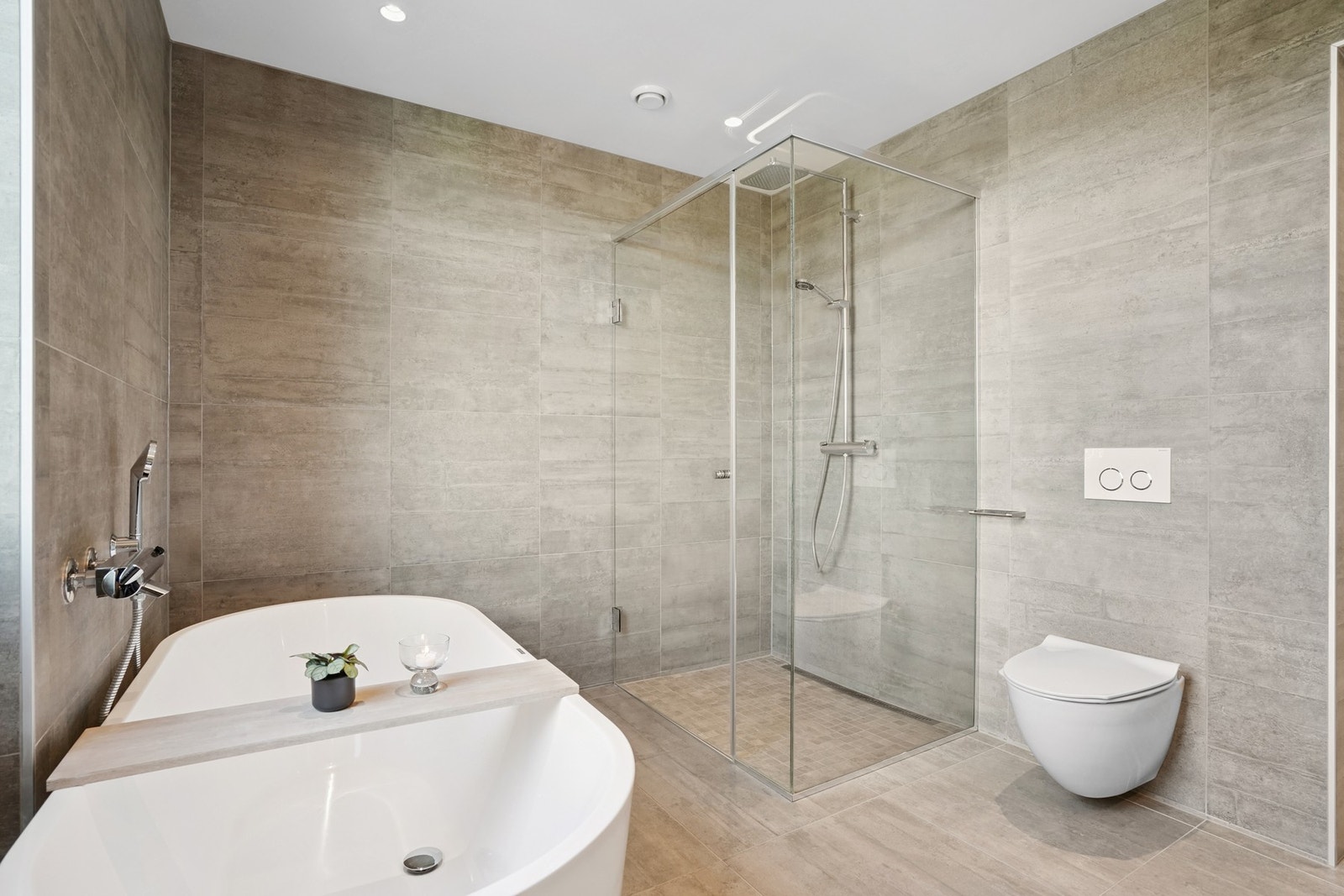 Badet er utstyrt med vegghengt toalett, dusjnisje med glassdører og badekar. Galleribilde