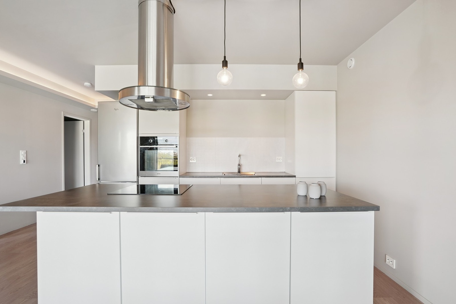 Hvitevarer som oppvaskmaskin, induksjonstopp og stekeovn. Frittstående kjøleskap. Kjøkkenventilator med avtrekk ut. Galleribilde