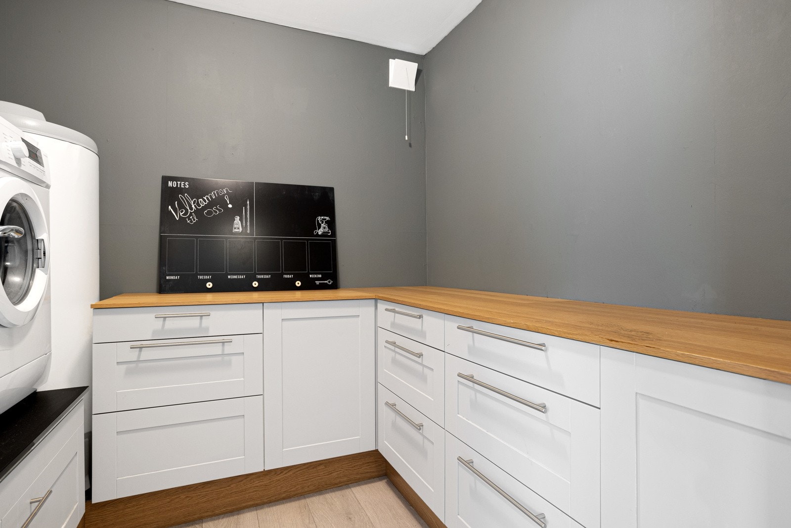 Praktisk innredet vaskerom med gode arbeidsflater, godt med skap-og skuffeplass, samt mulighet for å sette vaskemaskin og tørketrommel i god arbeidshøyde Galleribilde