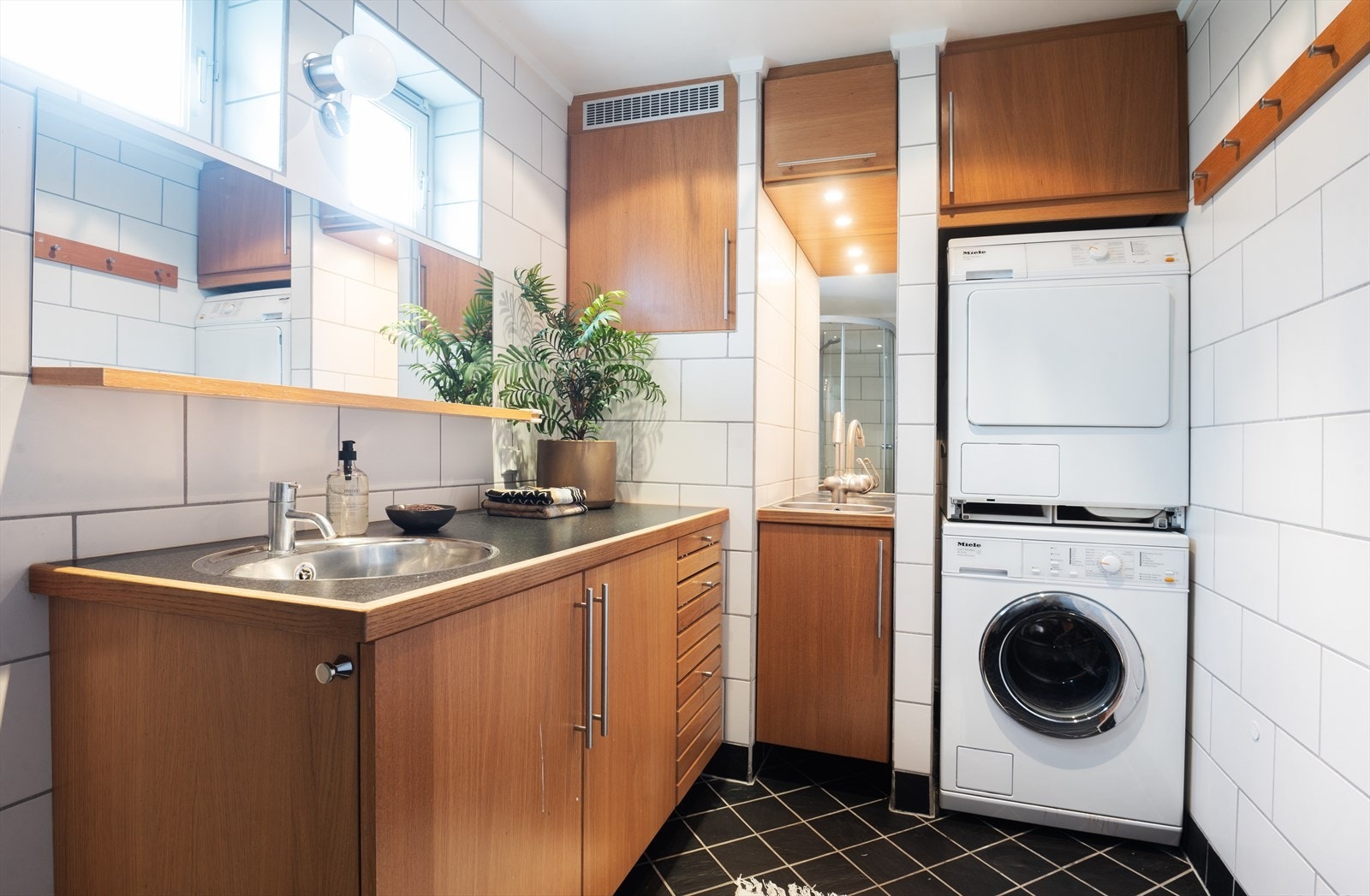 Bad/vaskerom er innredet med servant, overhengende speil med hylle, dusjkabinett og vegghengt toalett. Galleribilde