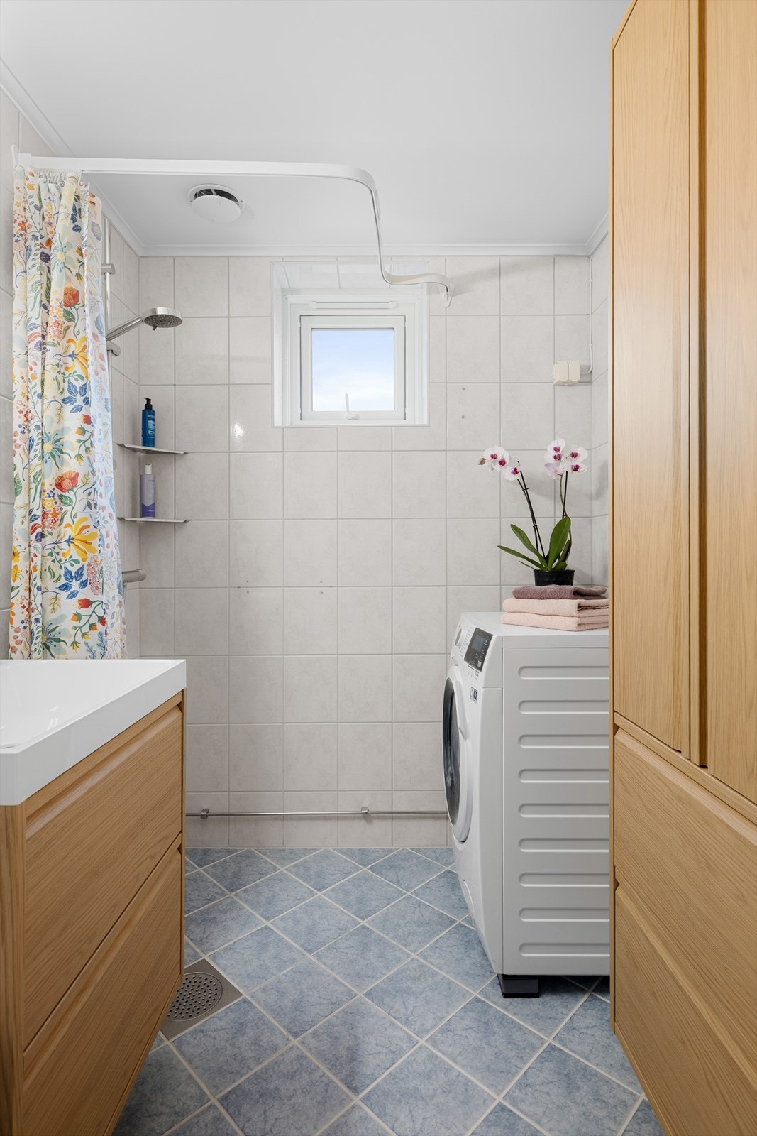 Badet har opplegg for vaskemaskin og et praktisk høyskap for ekstra oppbevaring. Galleribilde