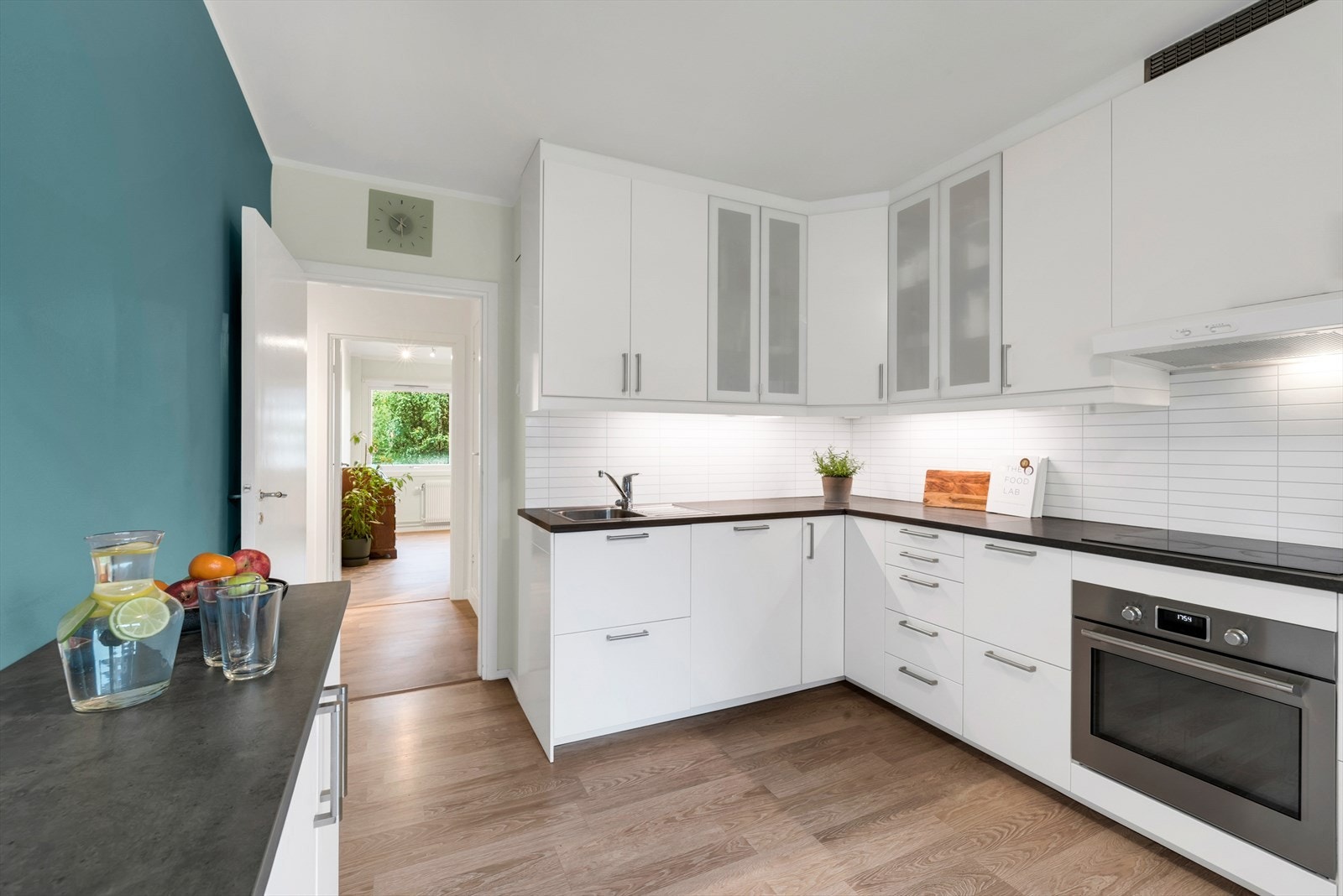 Kjøkkeninnredning med glatte fronter og vitrineskap gir rikelig med oppbevaringsplass. Galleribilde