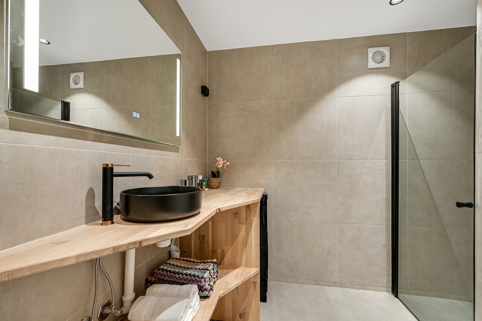 Badet har fliser på gulv og vegger, gulvvarme og er utstyrt med vegghengt toalett, servant, speil med lys og dusjhjørne med glassdør. I tillegg er det opplegg for vaskemaskin. Galleribilde