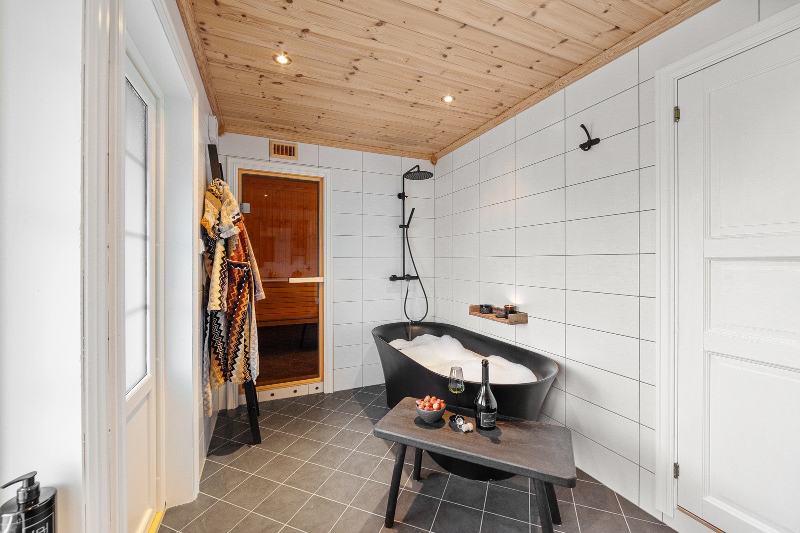 Flott bad som er innredet med badekar, gulv montert toalett og innredning med nedsunket servant med speil. Galleribilde