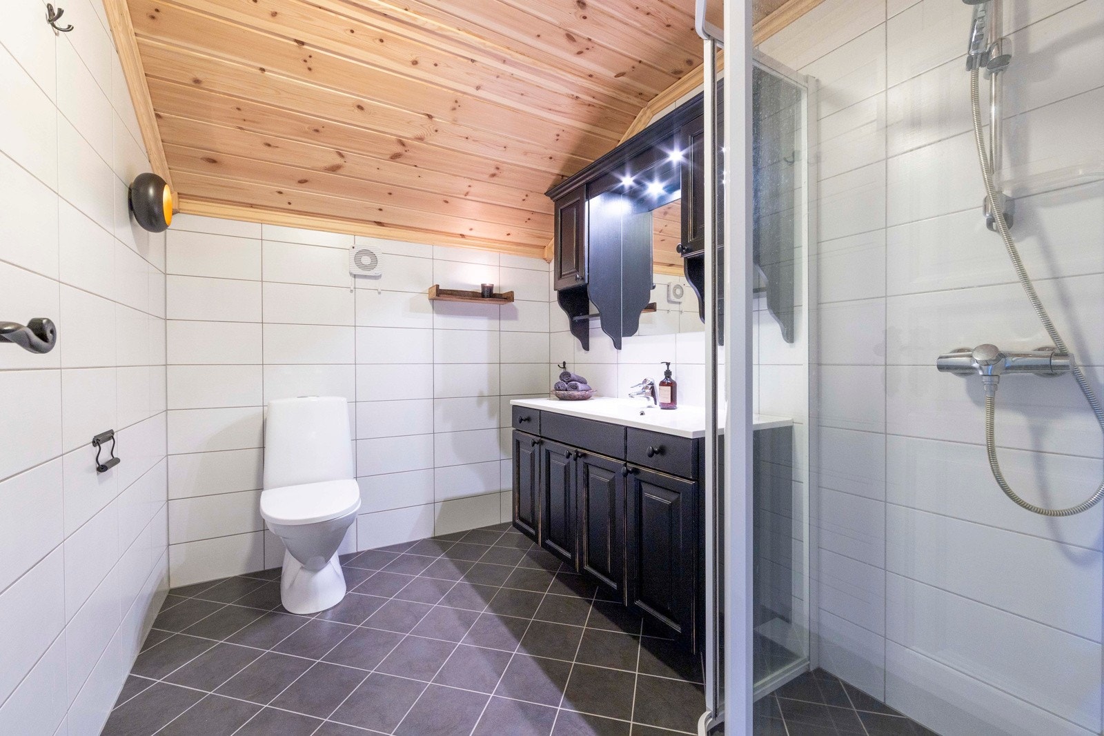 Badet på loftet er innredet med dusj hjørne med glass vegger, gulv montert toalett og innredning med nedsunket servant med speil. Galleribilde