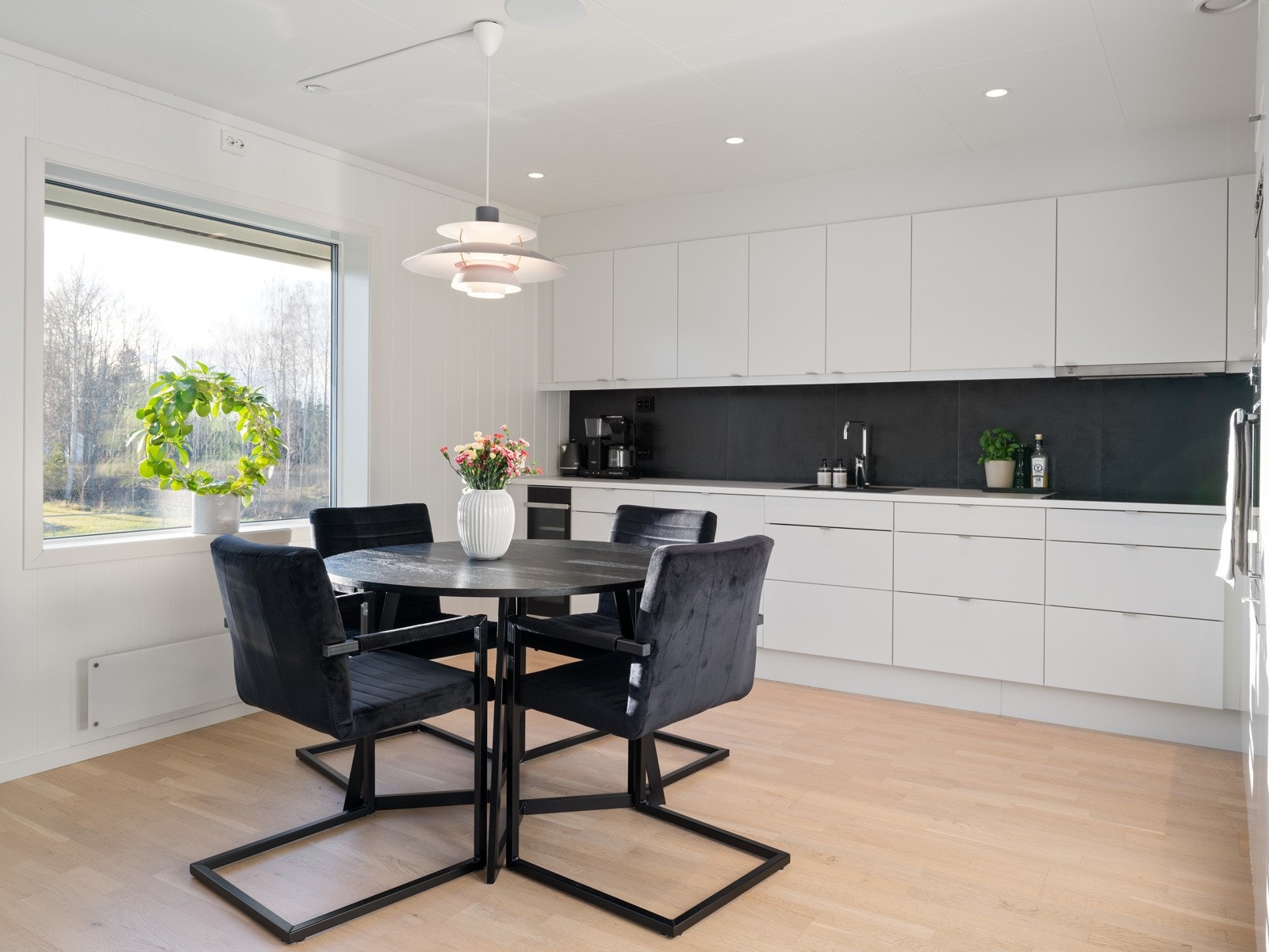 Hvit og moderne kjøkkeninnredning med integrert stekeovn, micro, kjøle- og fryseskap, oppvaskmaskin, induksjonstopp og vinskap. Galleribilde