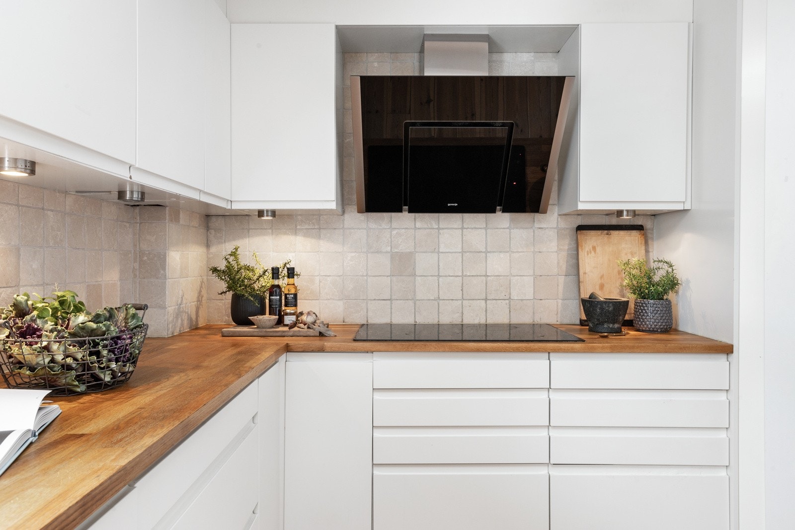 Kjøkkenet er både funksjonelt og estetisk tiltalende, med fliser mellom benkeplate og overskap, en stilren ventilator og en elegant nedfelt platetopp. Galleribilde