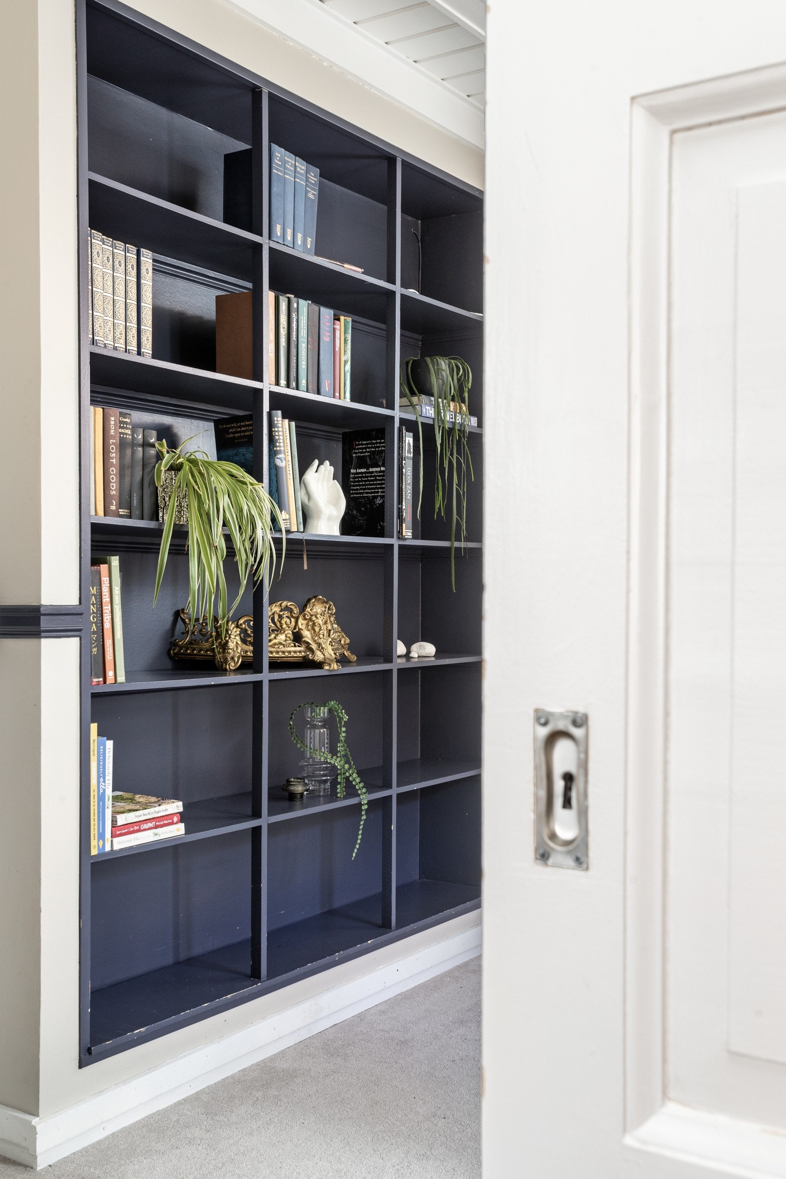 Denne høye bokhyllen er integrert og fungerer som et praktisk og dekorativt element. Galleribilde