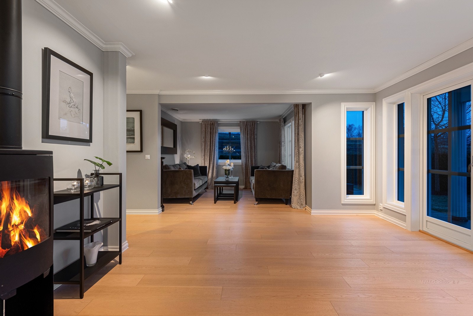 På kvelden kan du tenne opp i peisovnen for en lun atmosfære, mens downlights i taket skaper en naturlig inndeling av rommet Galleribilde