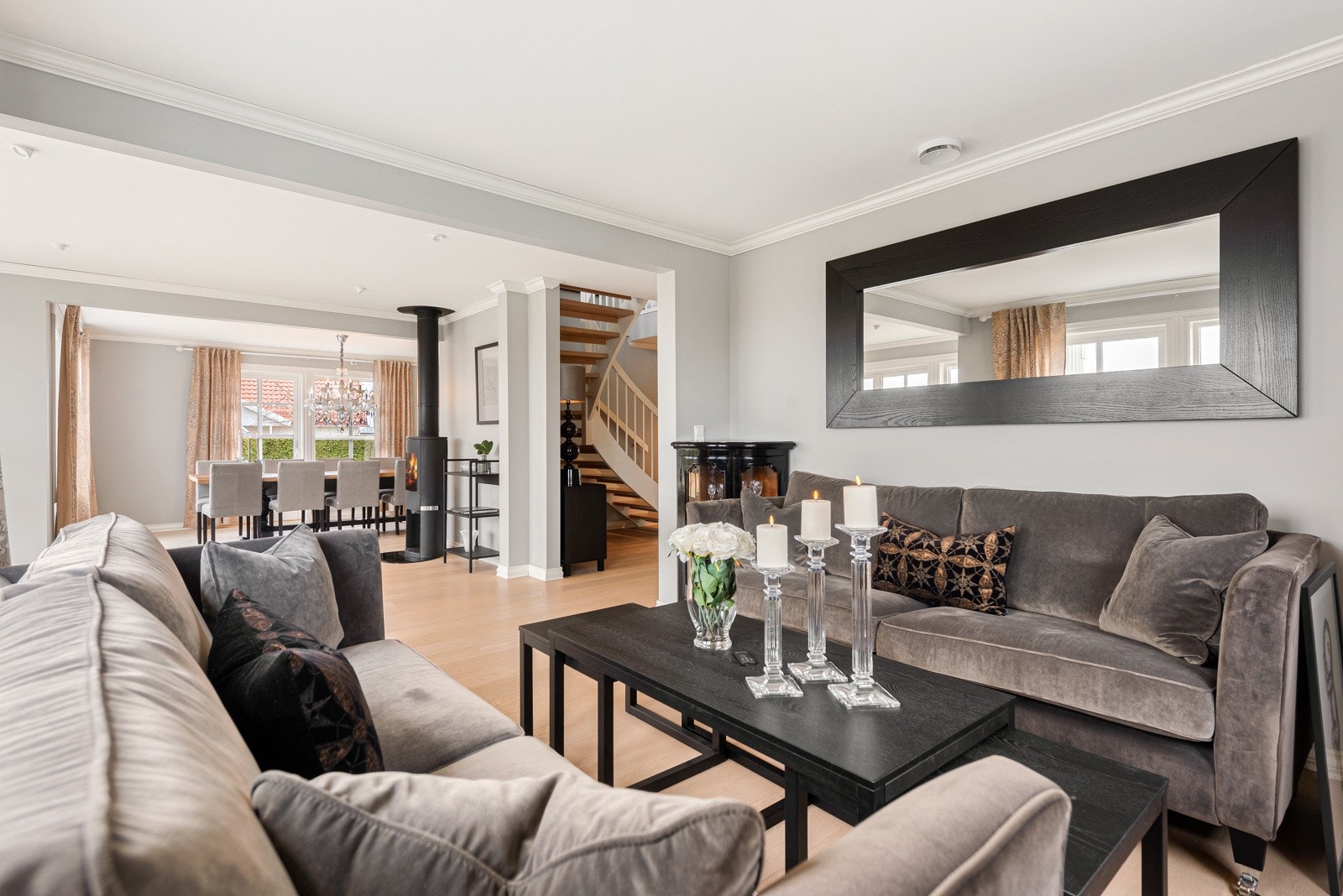 Med store åpninger mellom rommene og enstavsparkett som går igjen i etasjen føres du videre inn i stue og spisestue Galleribilde