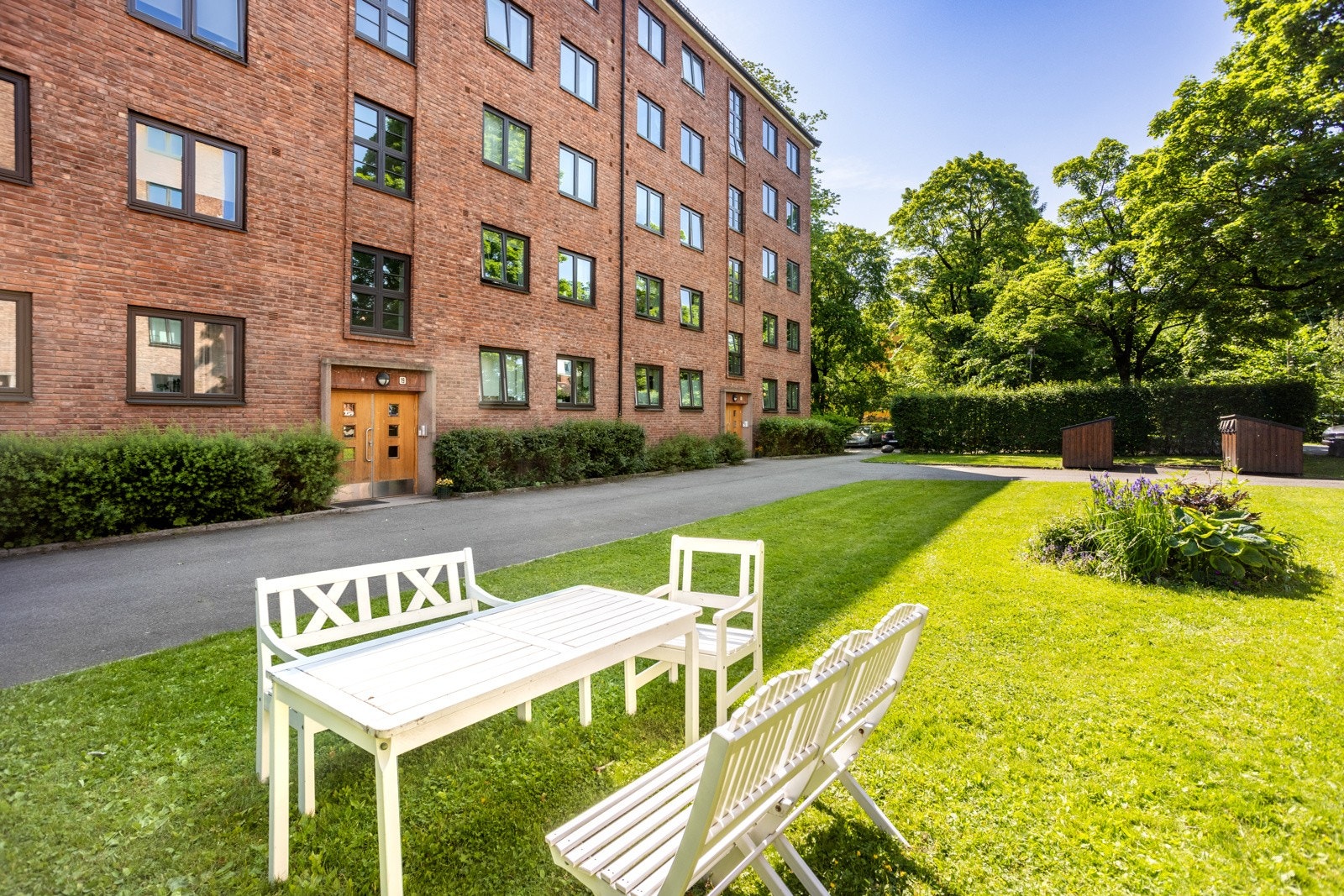 Tomten er pent opparbeidet med plen, beplantning, trær og sittegrupper. Galleribilde