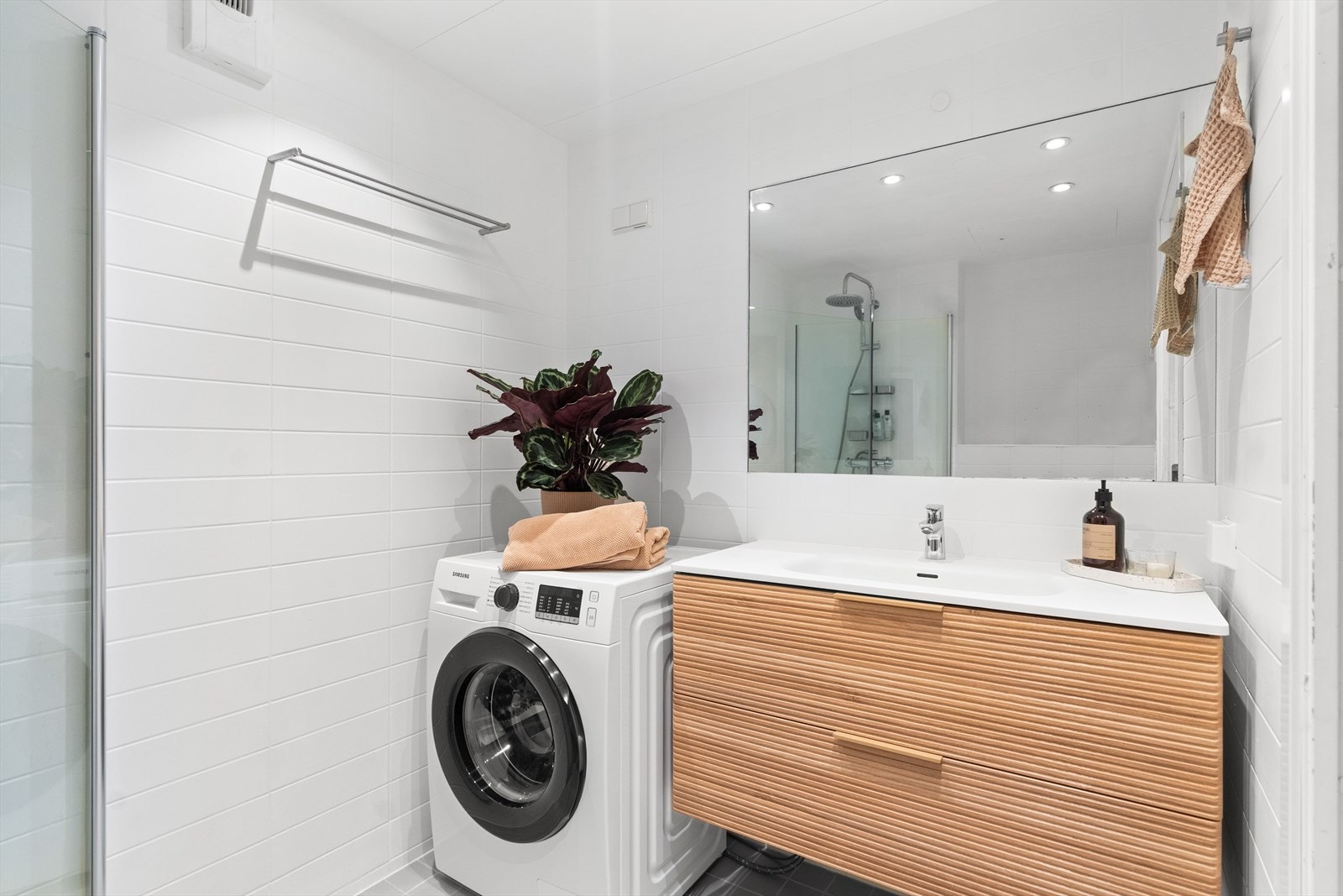 Rommet har dusj på gulv med dører i herdet glass, veggfestet klosett samt nyere servant med benkeskap. I tillegg har badet opplegg for vaskemaskin. Galleribilde