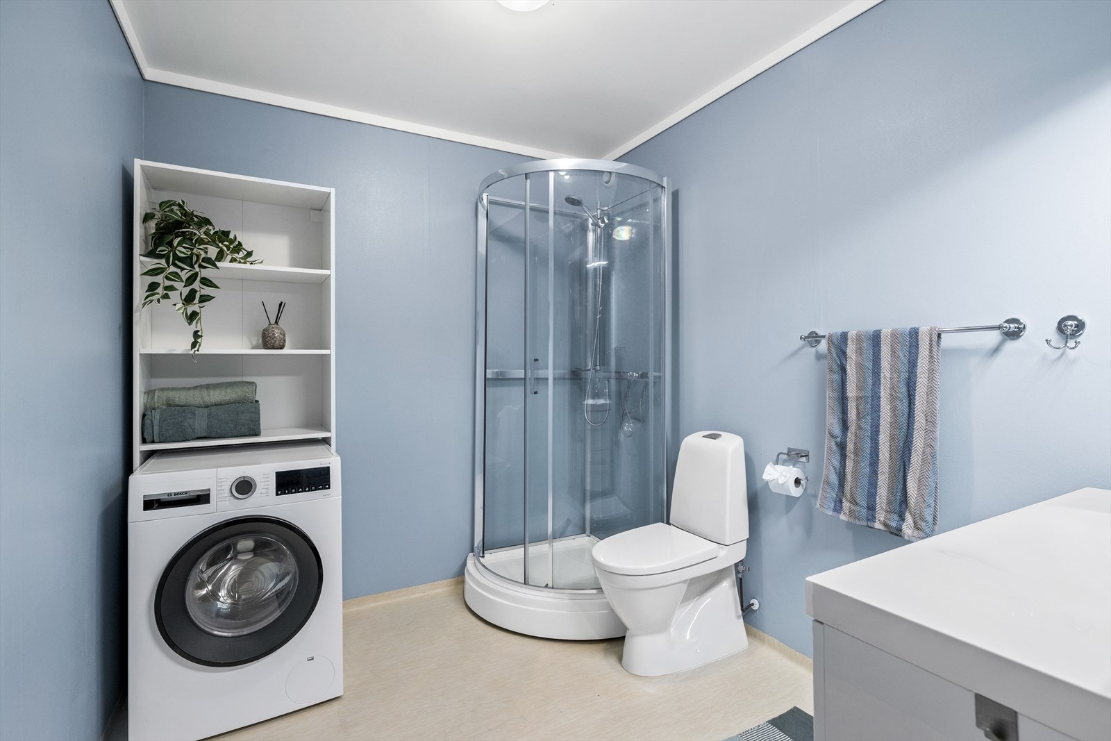 Badet er fra byggeåret og er svært romslig og funksjonelt. Det fungerer som et kombinert bad og vaskerom med dusjkabinett, toalett, servantinnredning og god plass med opplegg for vaskemaskin. Galleribilde