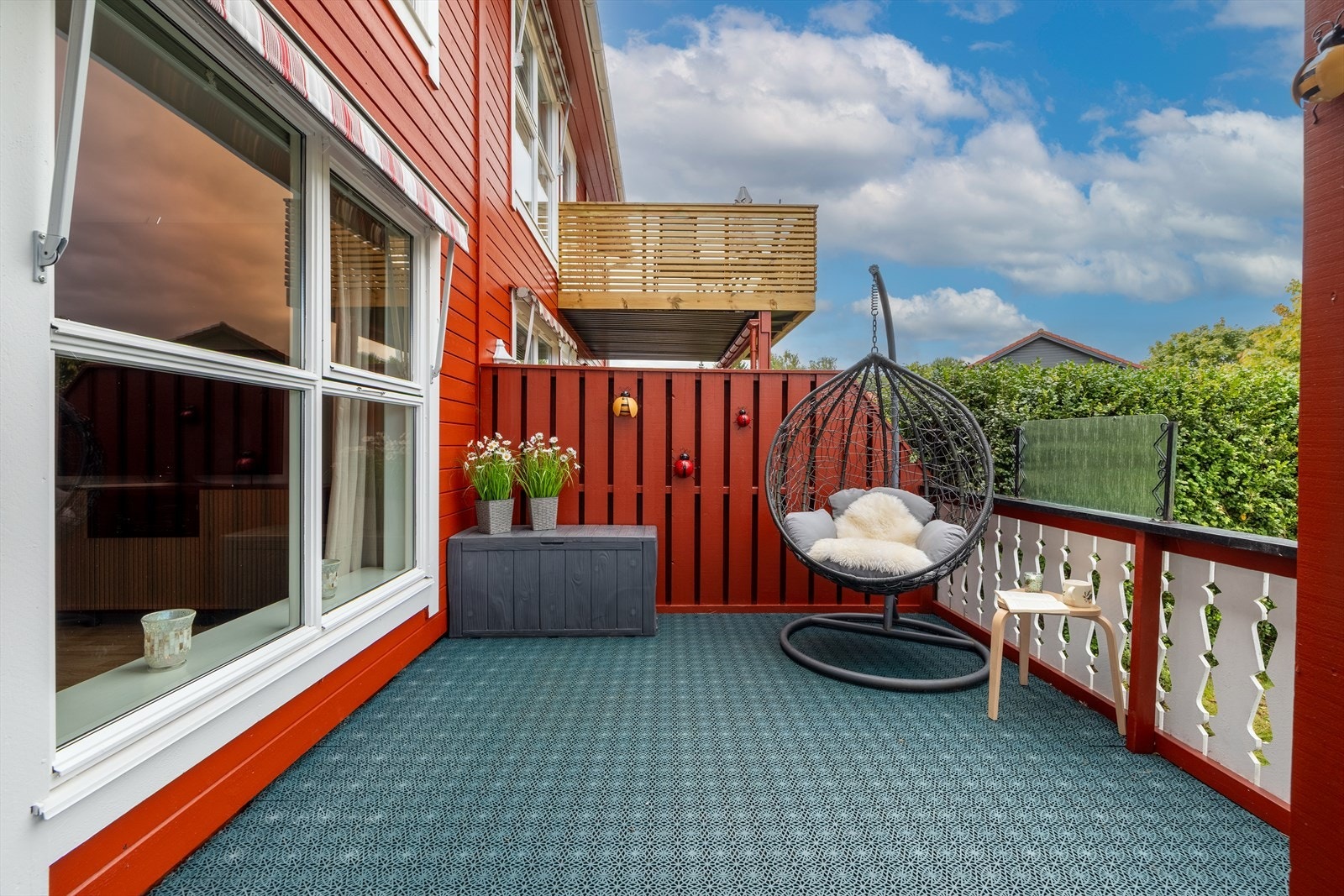 Terrassen er innrammet med rekkverk av tre og levegg mot nabo skjermer for innsyn. Galleribilde