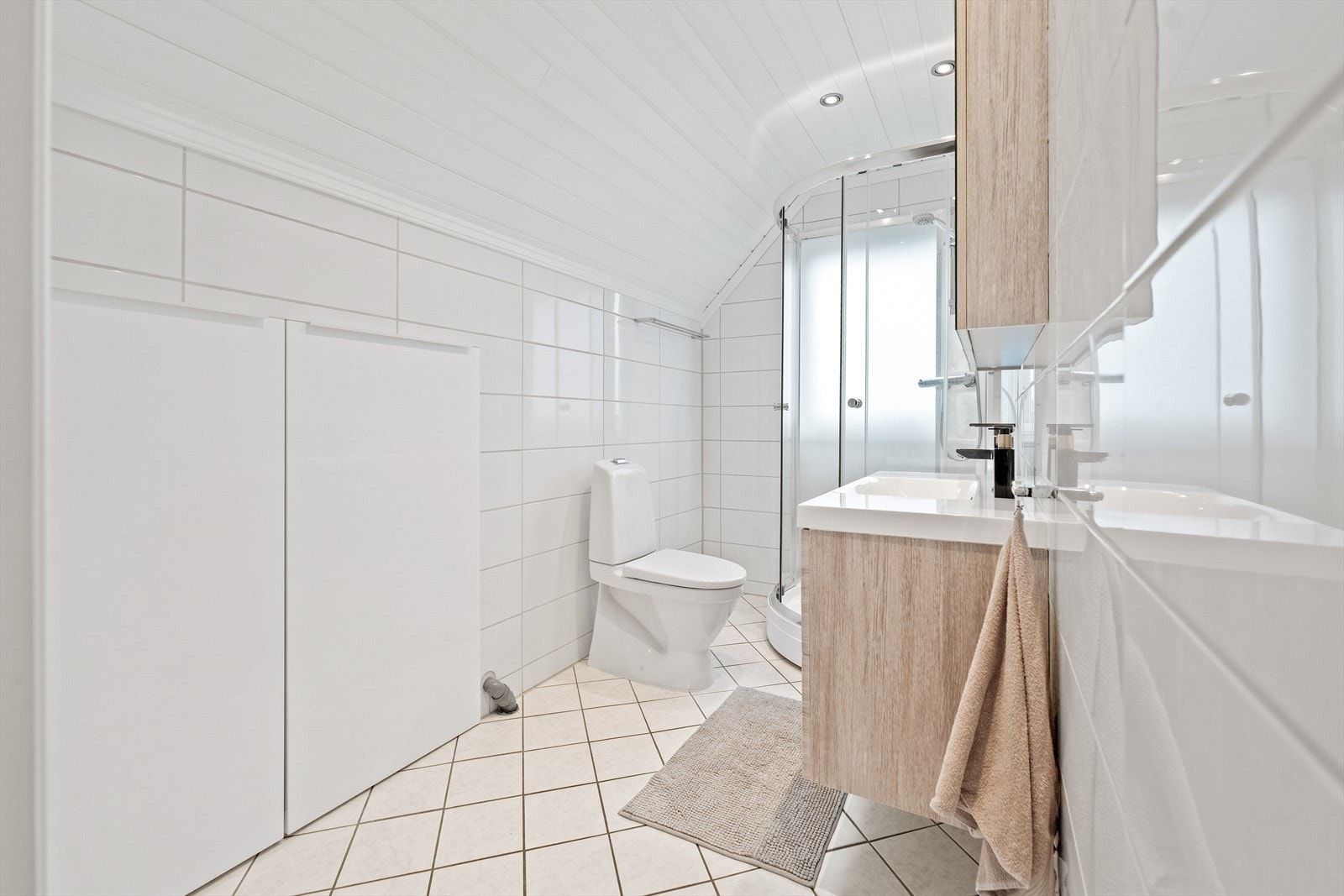 Det ene badet ligger i andre etasje og har en praktisk, plassbygd vaskesone skjult bak hvite skyvedører. Galleribilde